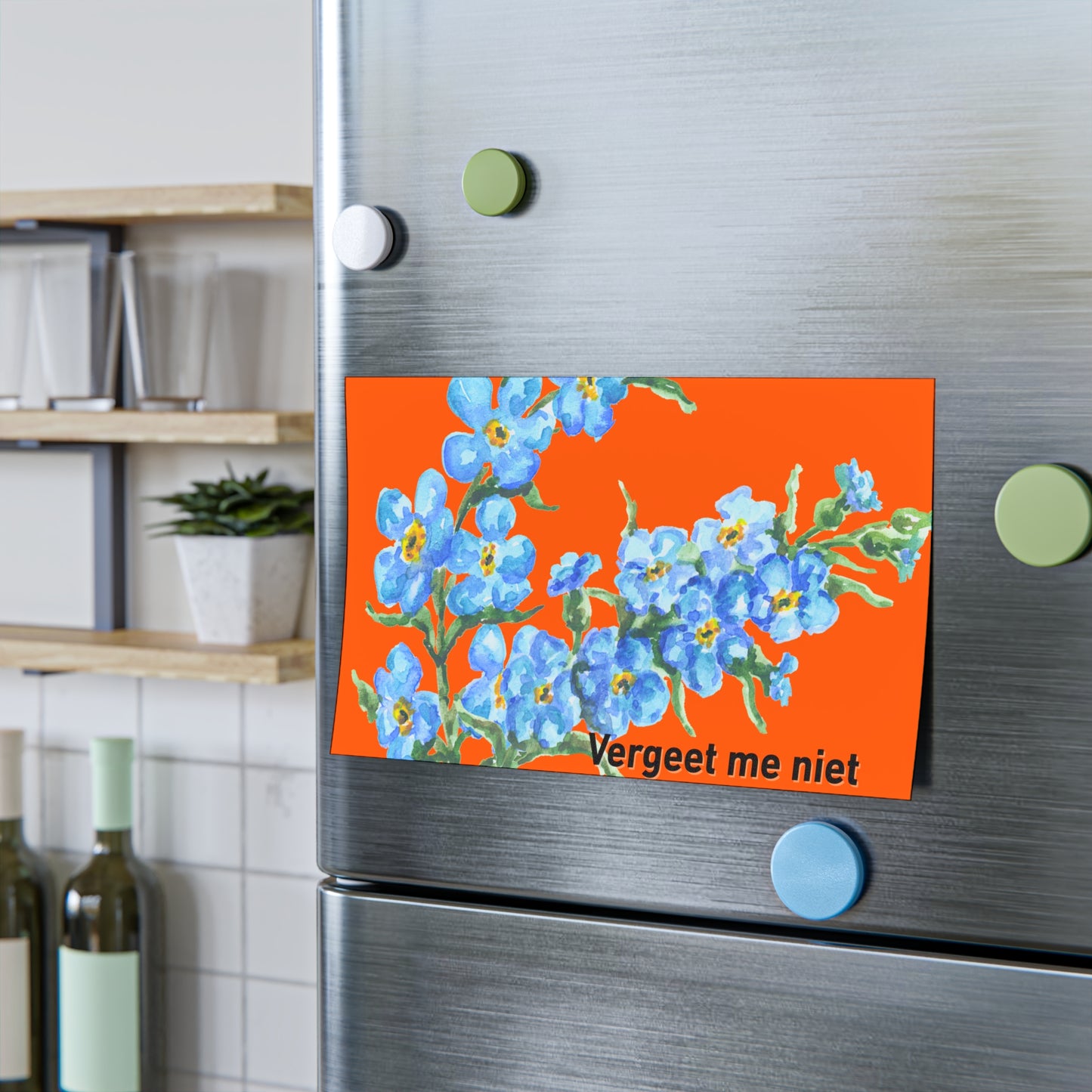 Close lifestyle view of orange "Vergeet me niet" forget-me-not pad magnetically held on fridge with kitchen backdrop