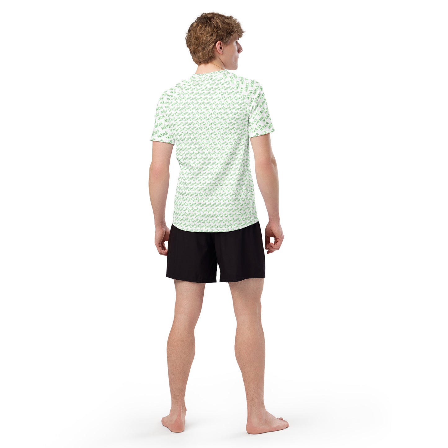 Back view of model in white men's rash guard with full green "skibidi" pattern, black shorts, barefoot