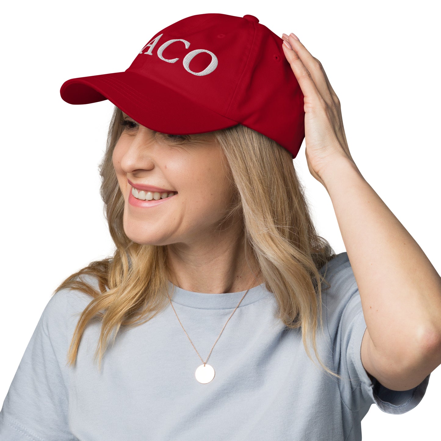 Side profile of blonde model hand on red dad hat's crown, white "TACO" embroidery visible, gray top