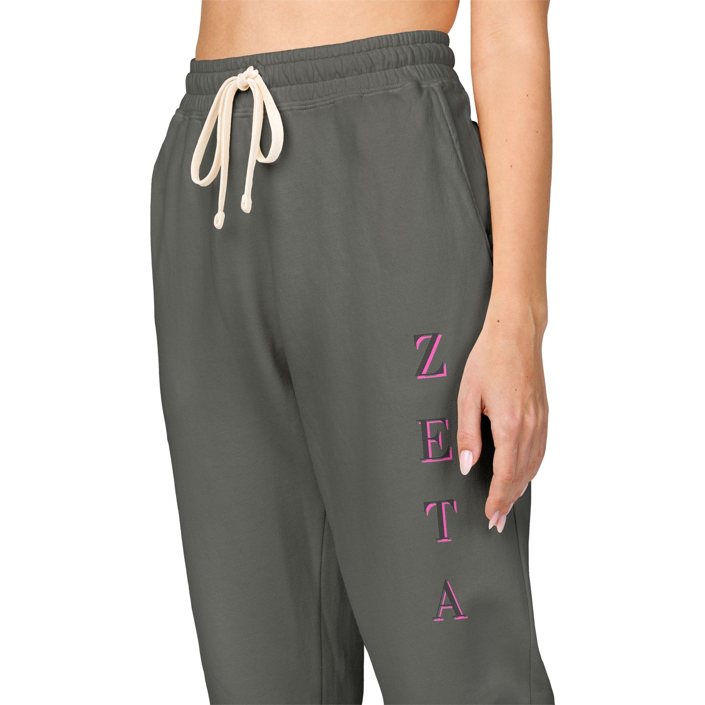 Side view model in charcoal Zeta sweatpants, pink "ZETA" lettering down leg, drawcord details pop