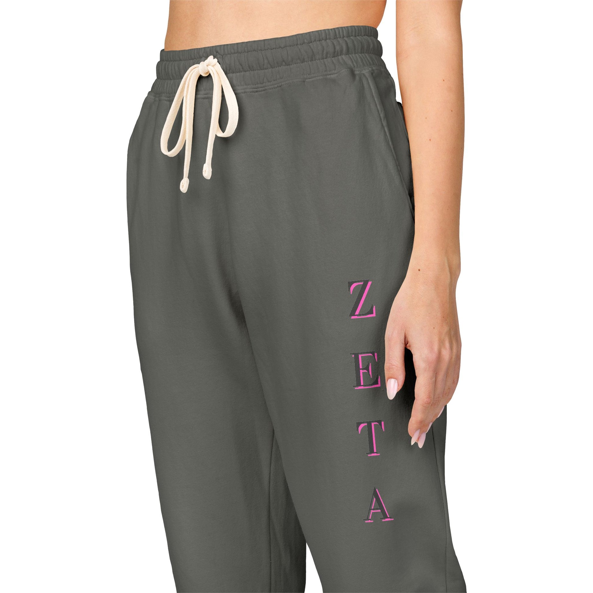 Side view model in charcoal Zeta sweatpants, pink "ZETA" lettering down leg, drawcord details pop