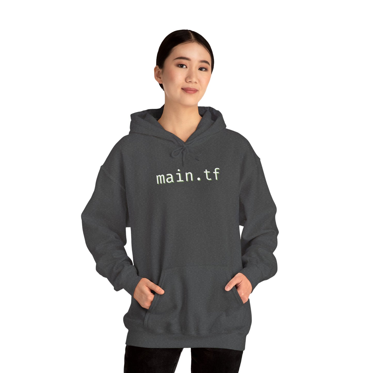 Woman in front of dark heather gray "main.tf" hoodie, light cyan text, hands in pockets