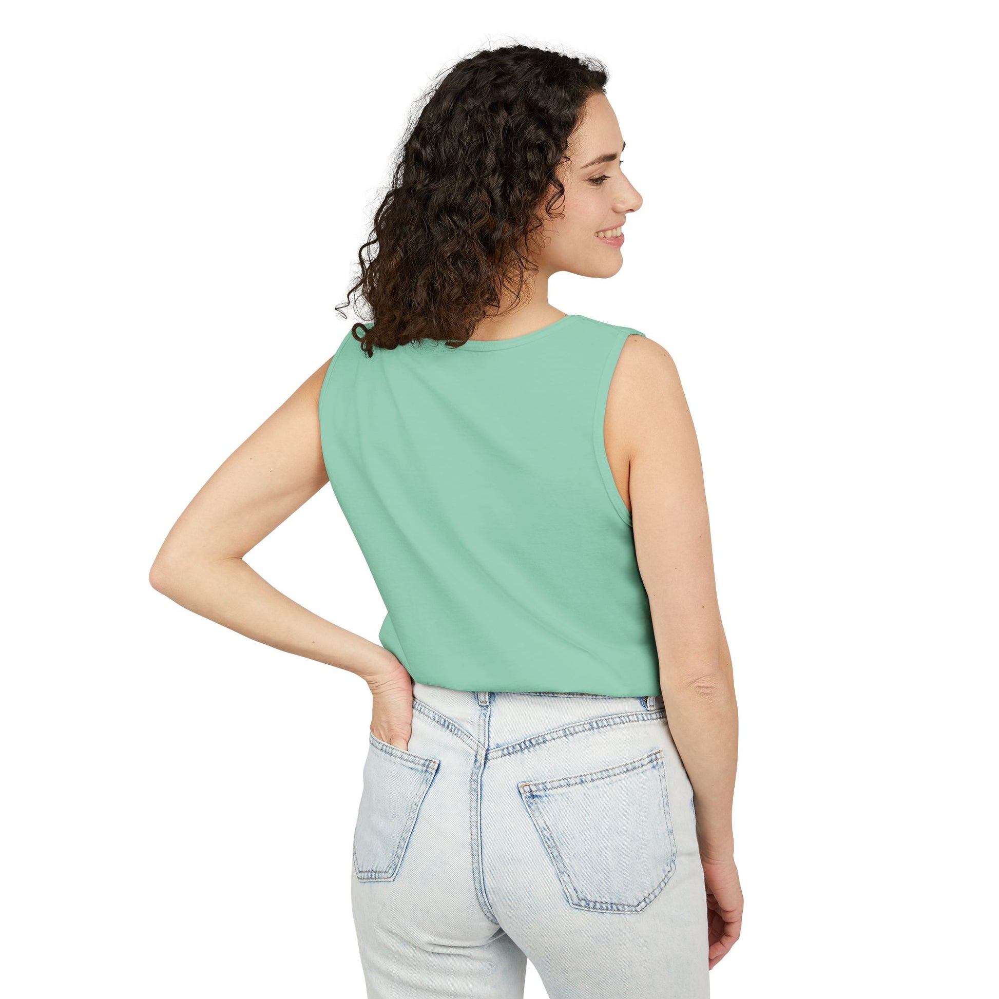 Side view of smiling woman in seafoam green tank top, hand on hip with light jeans