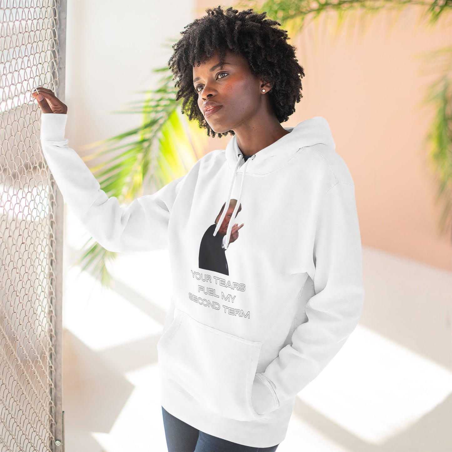 Curly-haired model posing in white Trump Flip Off hoodie, showing off the cheeky front print