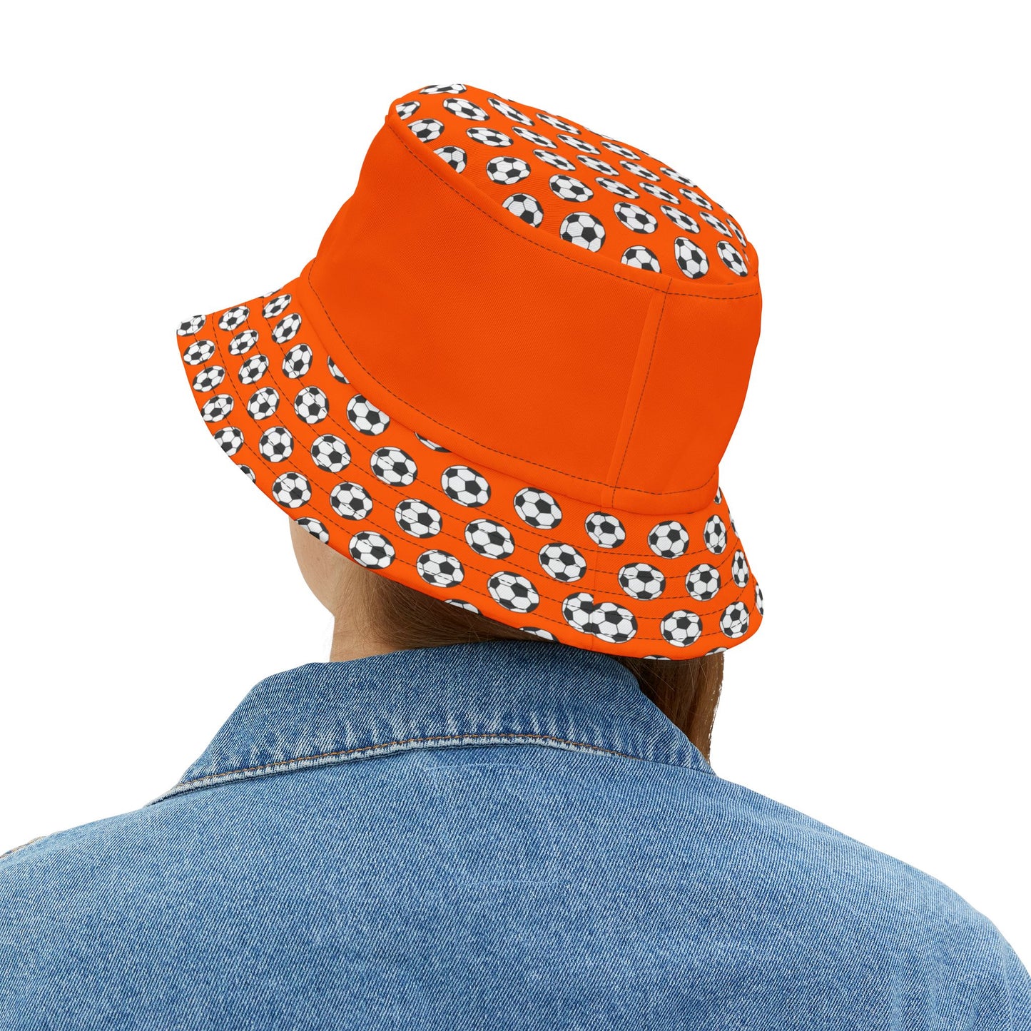 Back view of woman in orange bucket hat with draped black-and-white soccer ball panels, casual denim look