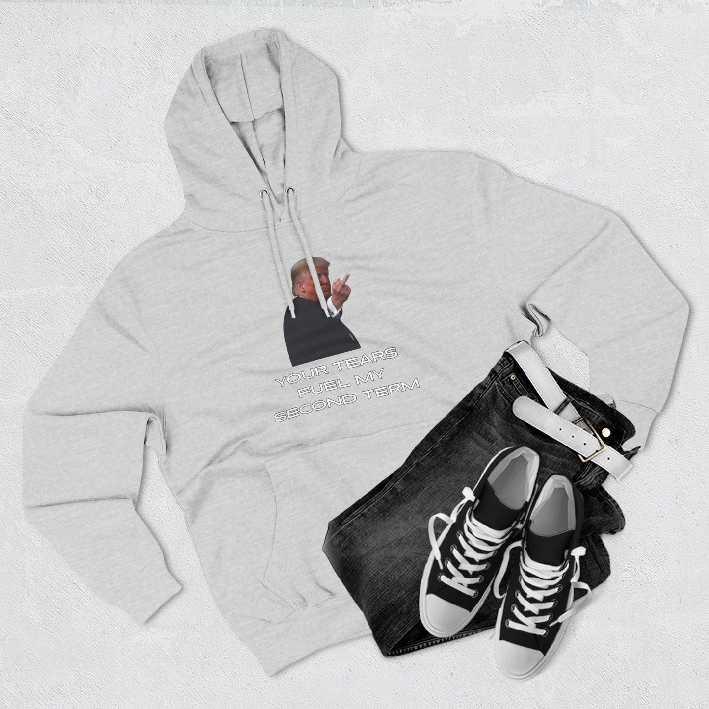 Flat lay of heather grey Trump hoodie front with dark jeans and white sneakers styling