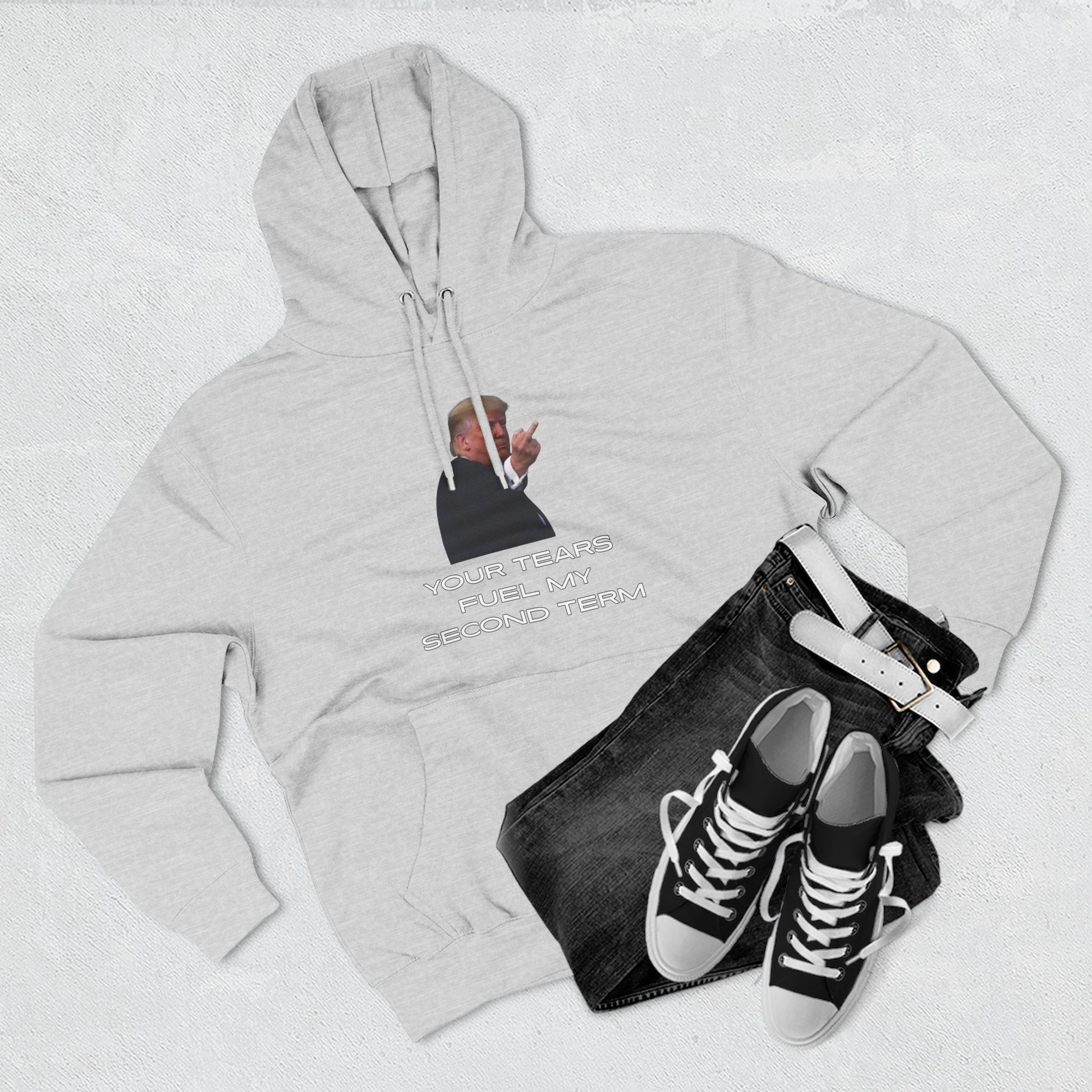 Flat lay of heather grey Trump hoodie front with dark jeans and white sneakers styling