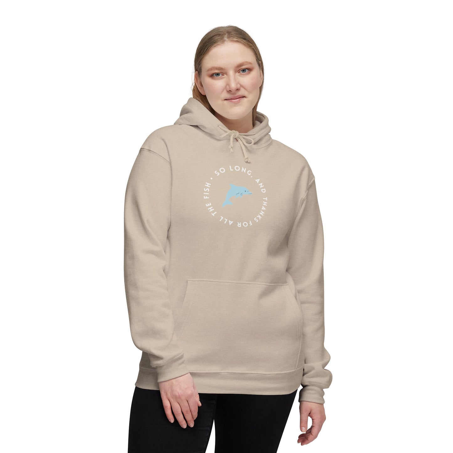Smiling woman models sand hoodie front, cheeky blue dolphin in "So long, and thanks for all the fish" white circle print