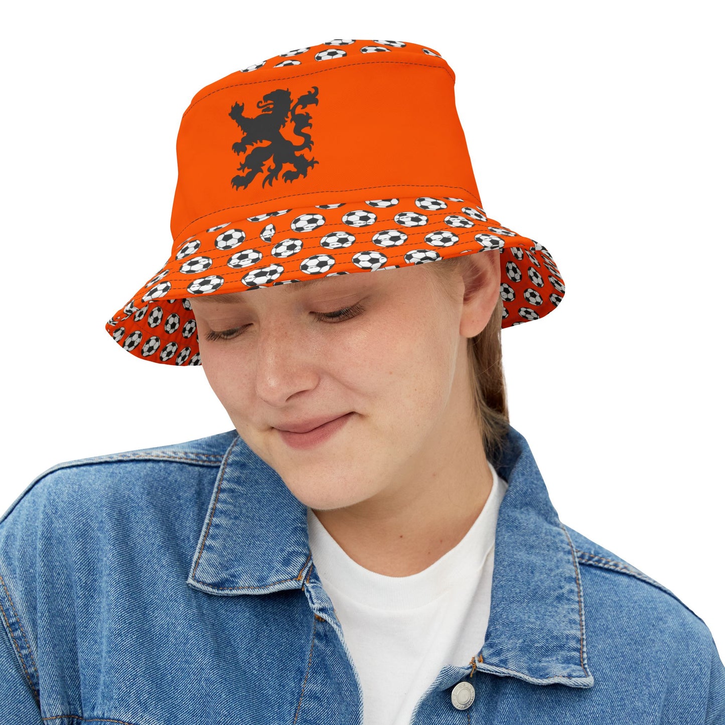 Playful woman frontish in orange bucket hat, black lion roaring above soccer-dotted brim