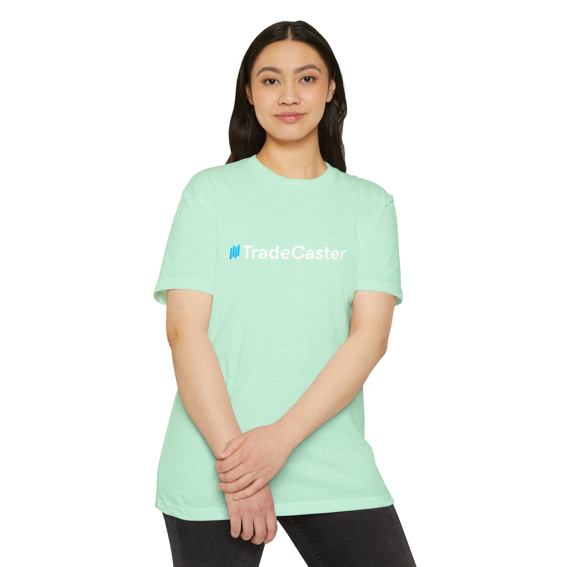 Female model in mint green unisex tee, front view with centered blue TradeCaster logo and white text, hands clasped casually