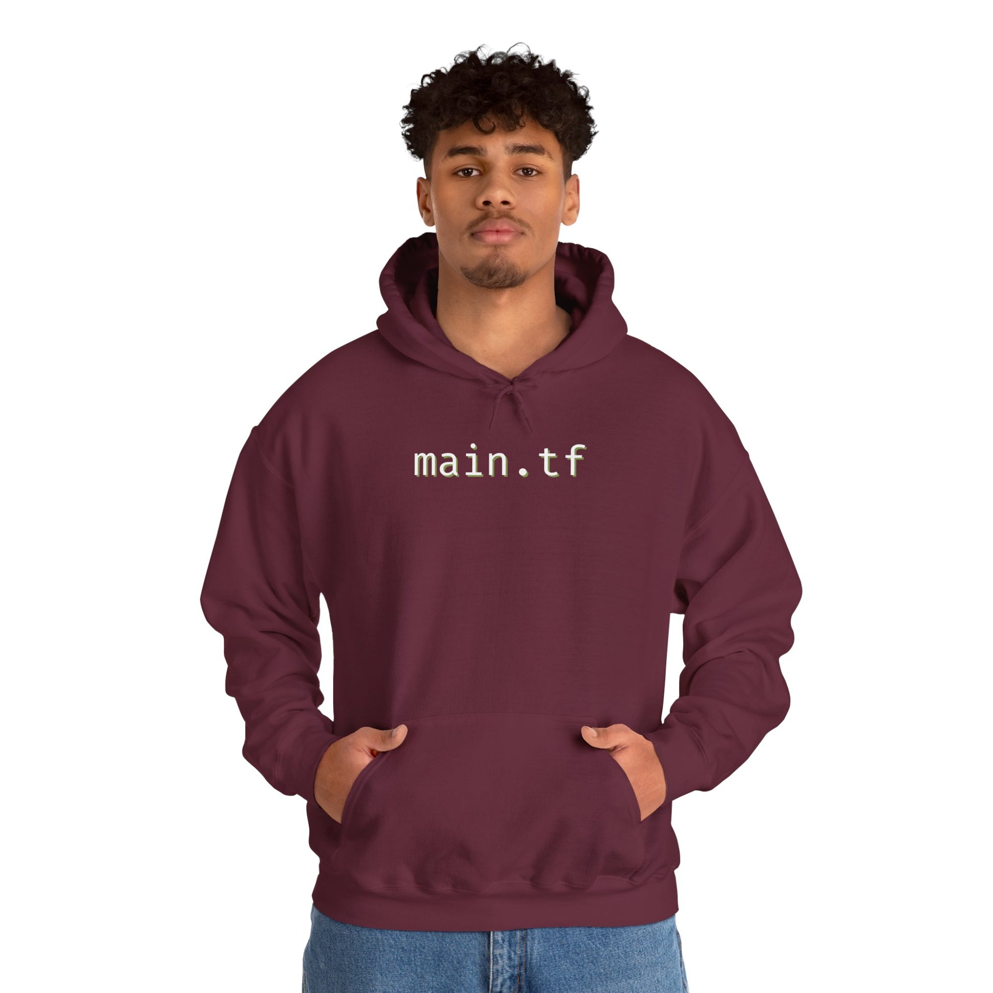 Curly-haired male model in maroon hoodie, bold white "main.tf" chest print, hands pocketed