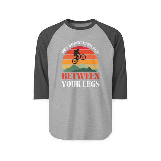 Front view of heather grey raglan shirt with black sleeves, "Put something fun between your legs" print and sunset MTB graphic