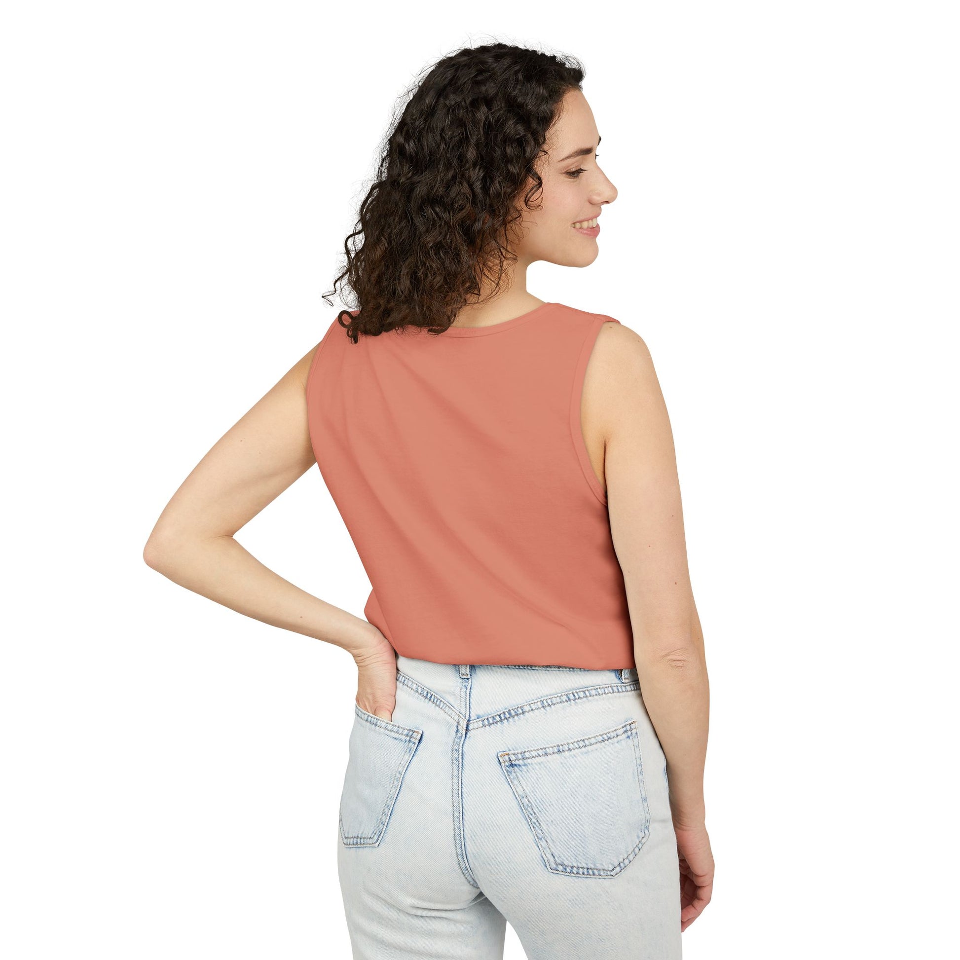 Side view of woman in peach tank top, hand on hip, light wash jeans