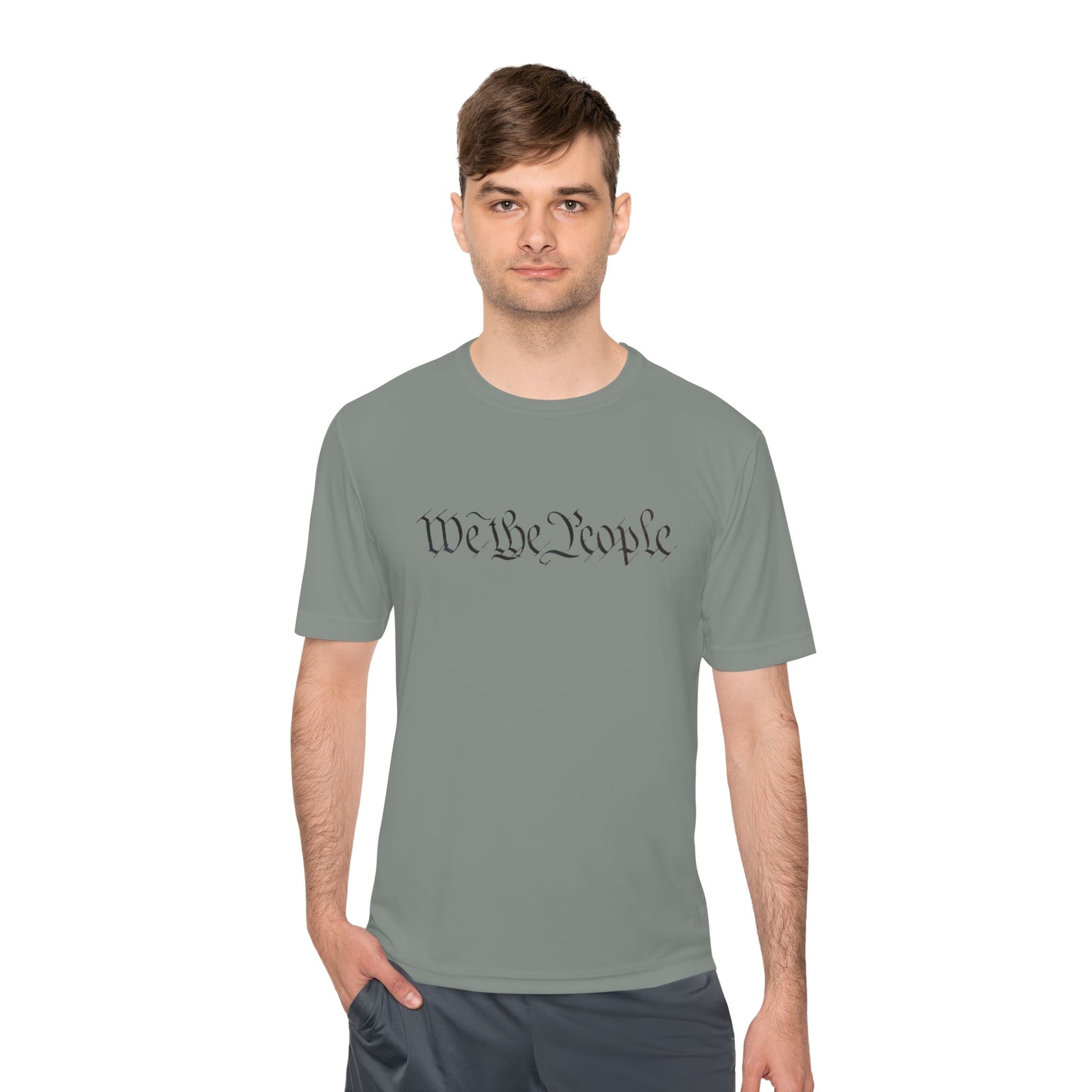 Male model owning the iron grey "We the People" moisture-wicking tee, hands in pockets