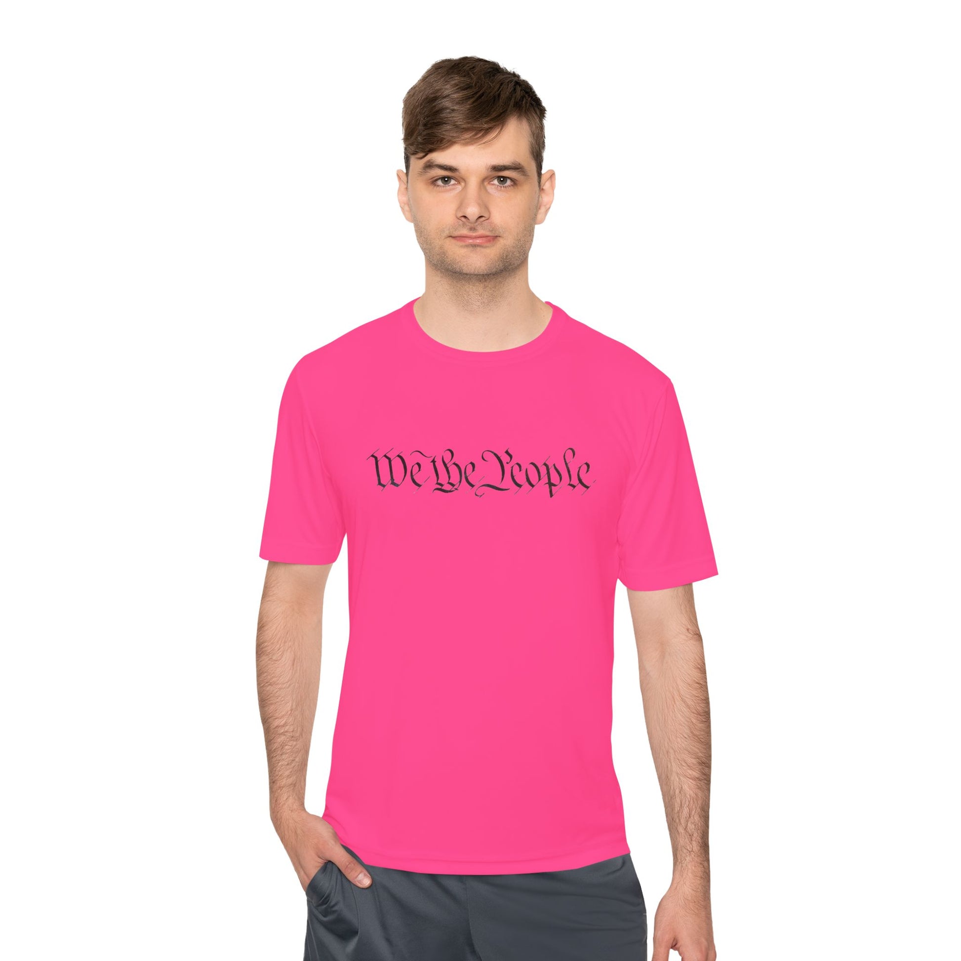 Male model front view in hot pink moisture-wicking tee with black cursive "We the People" script across chest