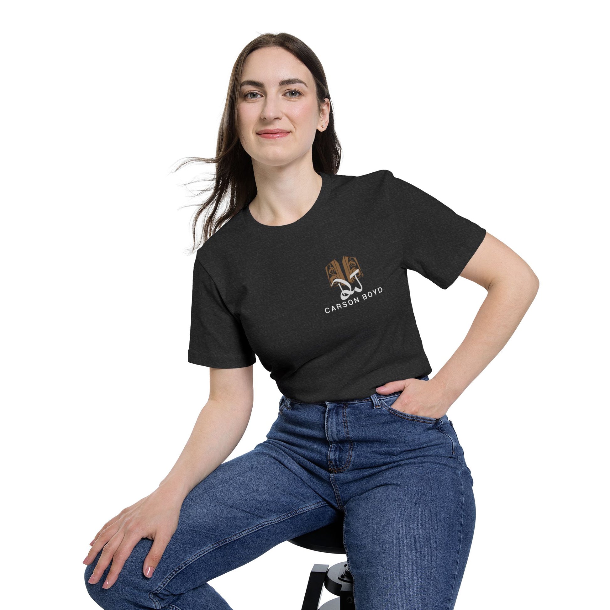 Female model hip-shot sit in dark heather gray tee, tan DJ Carson Boyd logo detail on left chest