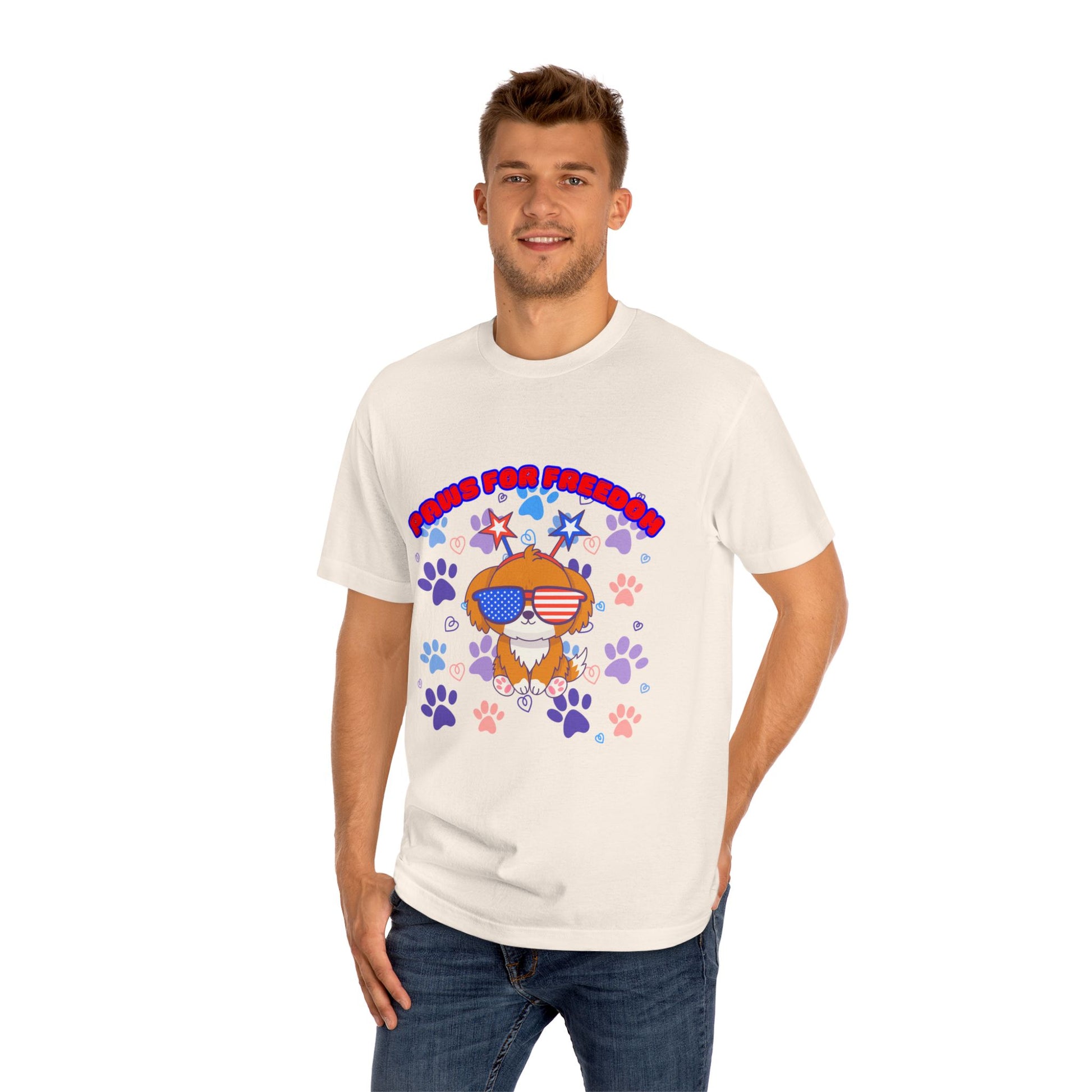 Male model in white 'Paws for Freedom' tee, front view: orange dog with shades & flag bandana amid colorful paws & stars