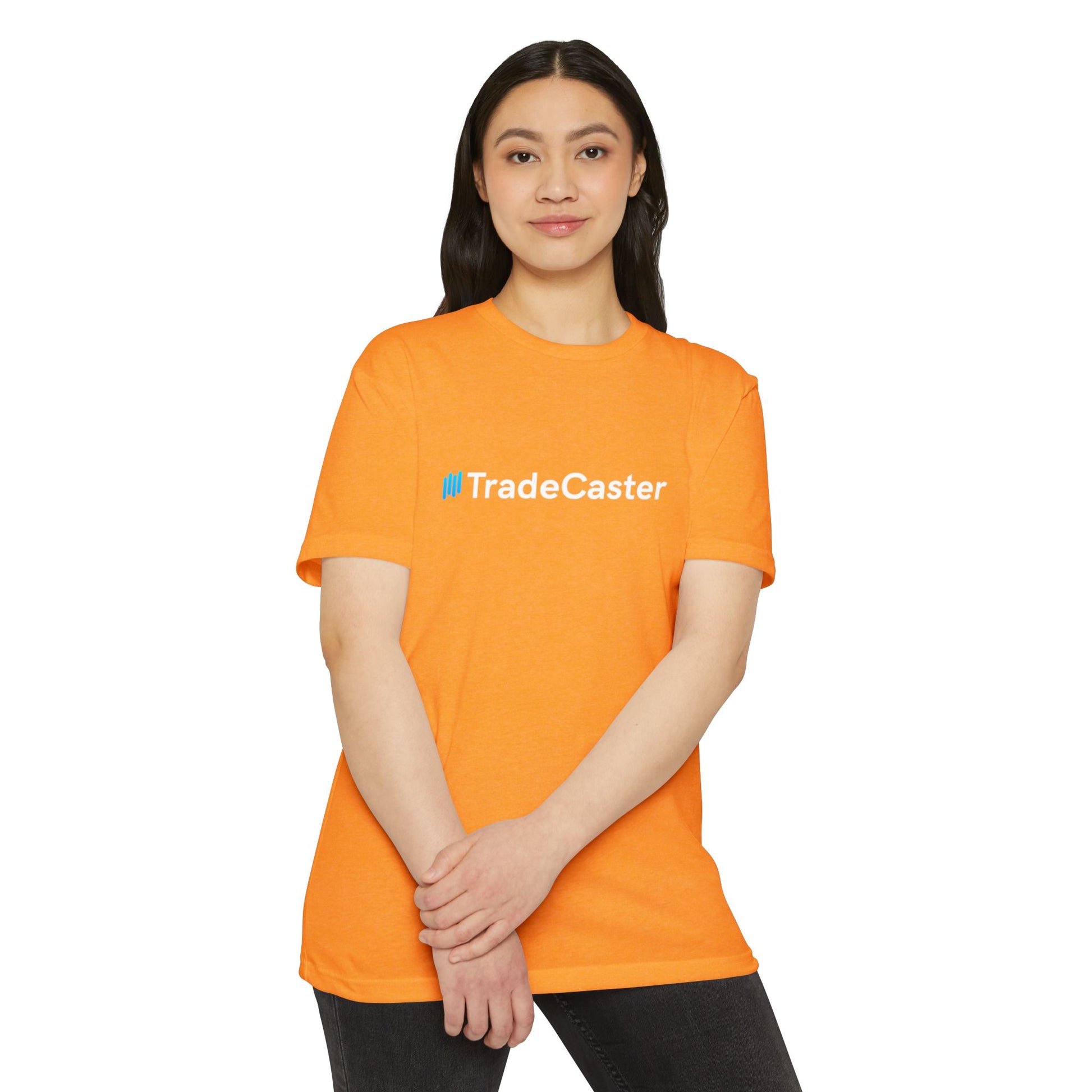 Female model in bright orange TradeCaster unisex tee, front view with cyan logo, casual hands-clasped pose