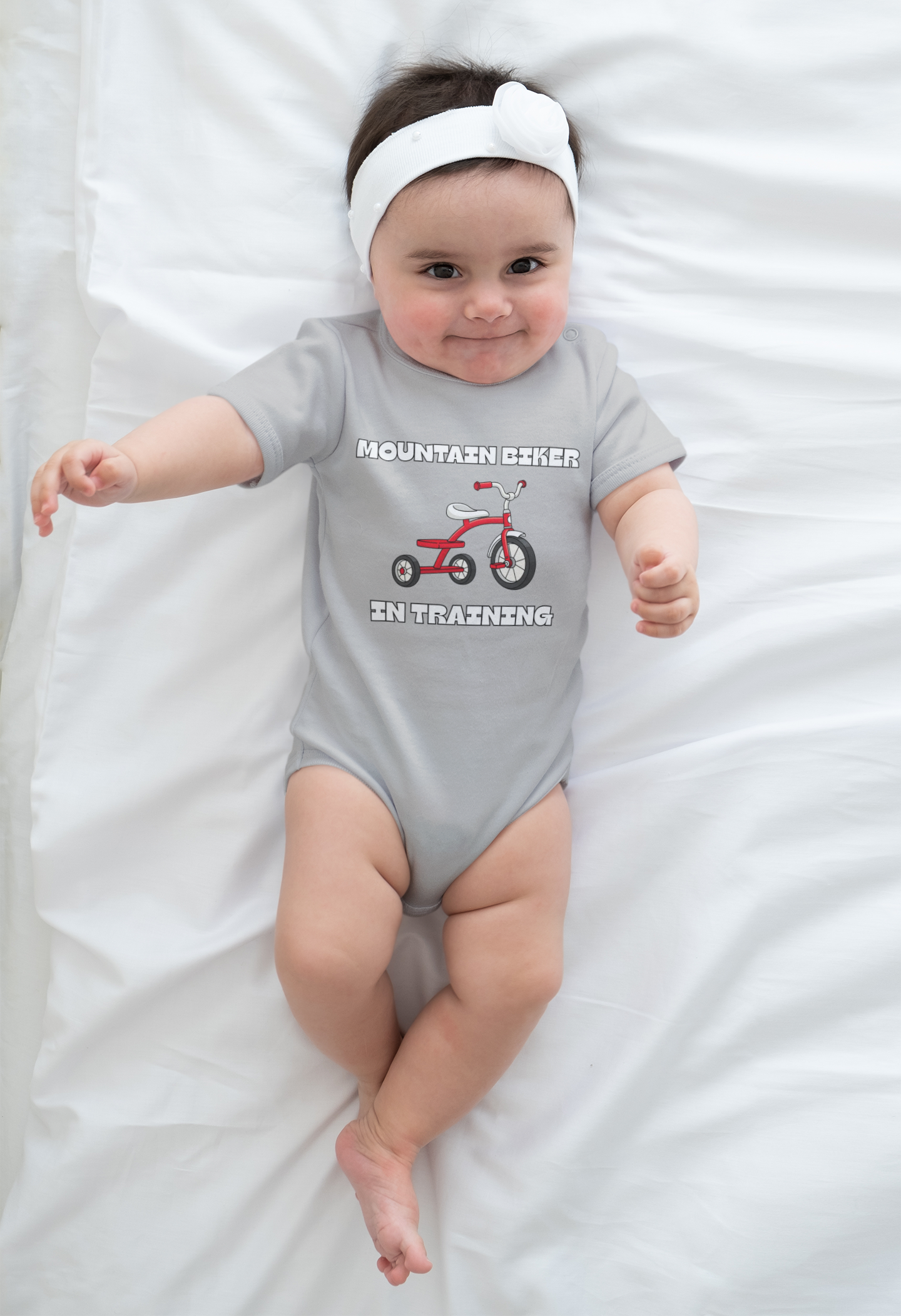 Baby model in butter yellow 'Mountain Biker in training' tee with red tricycle
