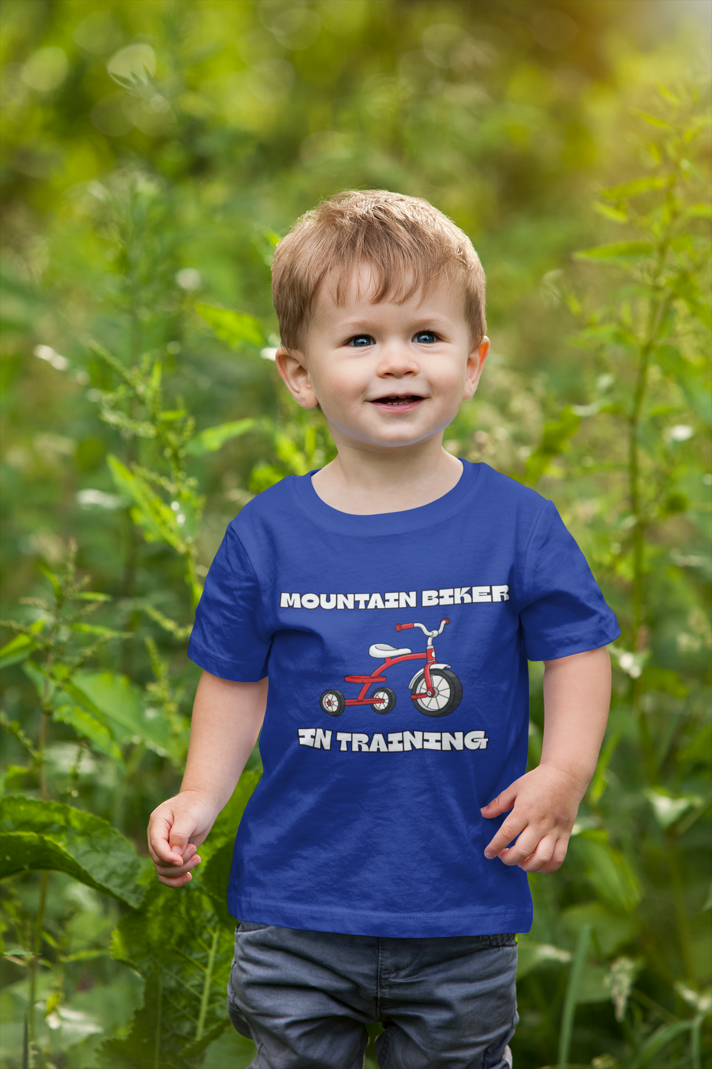 Boy wearing blue 'Mountain Biker in training' red tricycle infant tee - outdoor front view