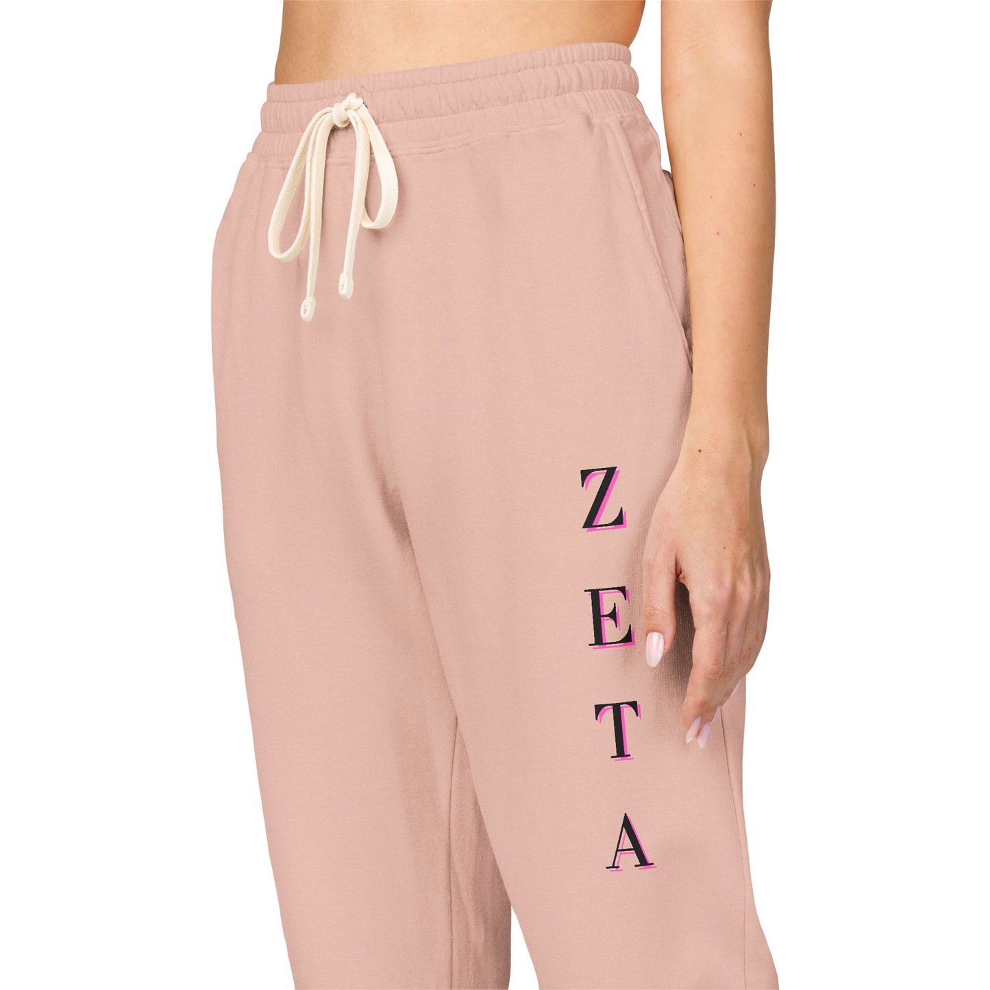 Side angle model in peachy sweatpants, magenta "ZETA" down leg, drawstring flex