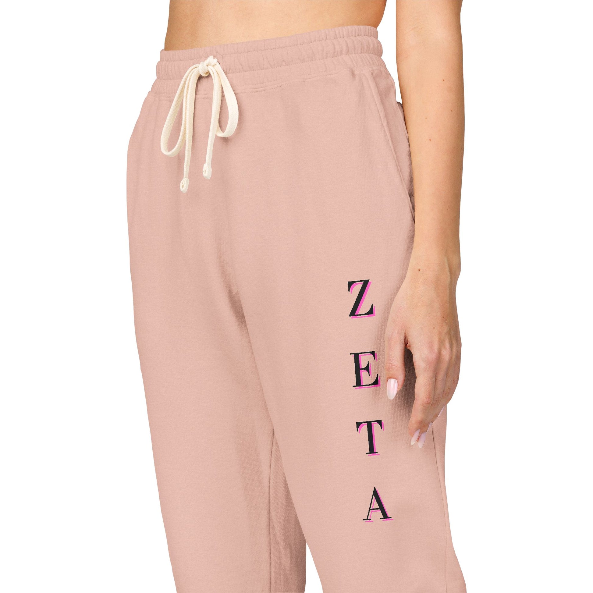 Side angle model in peachy sweatpants, magenta "ZETA" down leg, drawstring flex