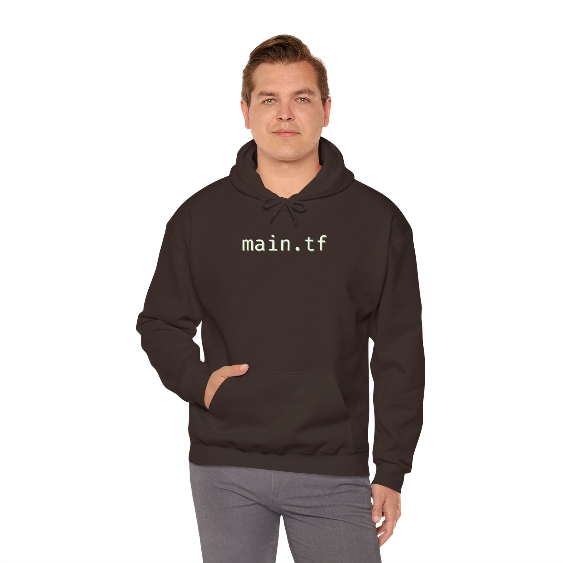 Man modeling front of dark heather gray hoodie with "main.tf" in light cyan monospace on chest, hands in pockets