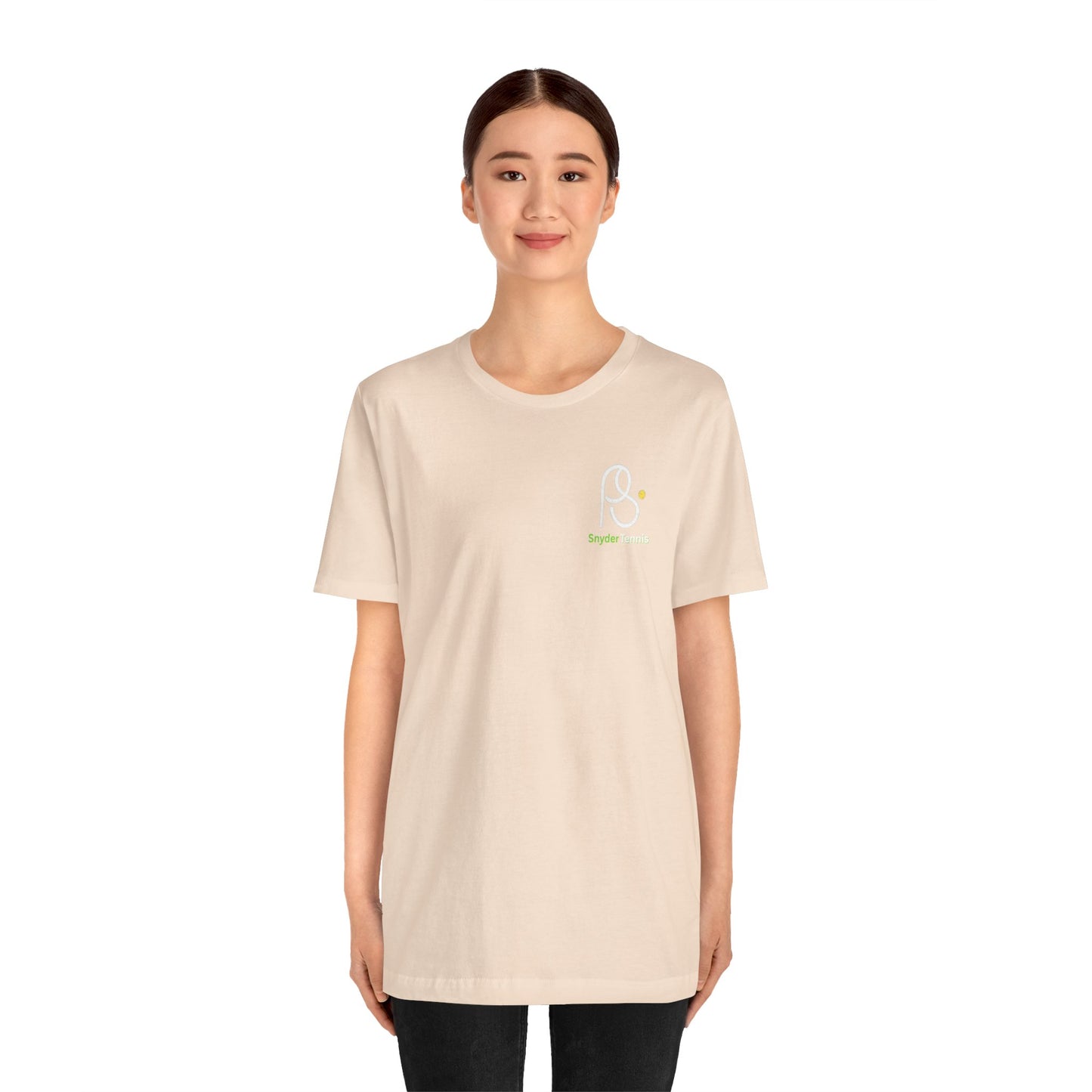 Female model front view rocking beige Coach Pete Snyder tennis tee with PS chest logo and black pants