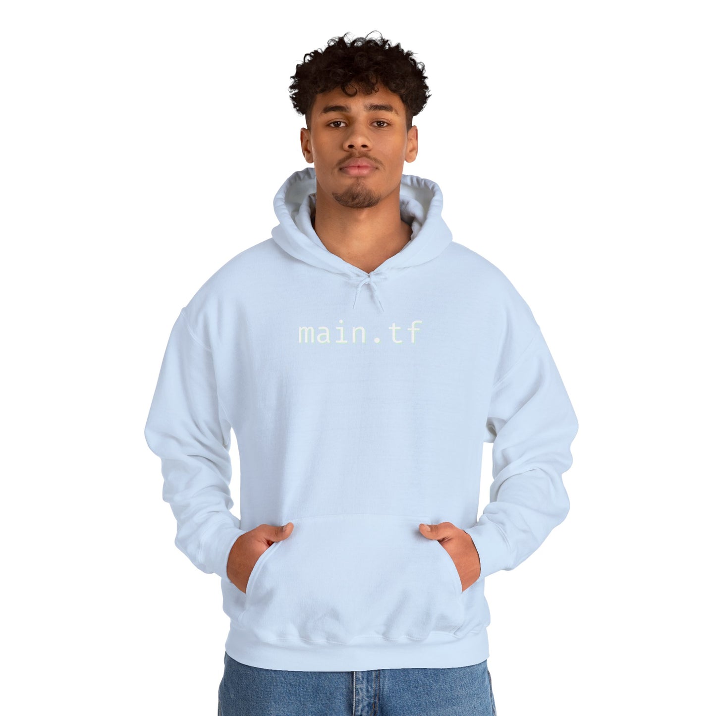 Smiling female model in light blue "main.tf" hoodie, hands in kangaroo pocket, black pants vibe