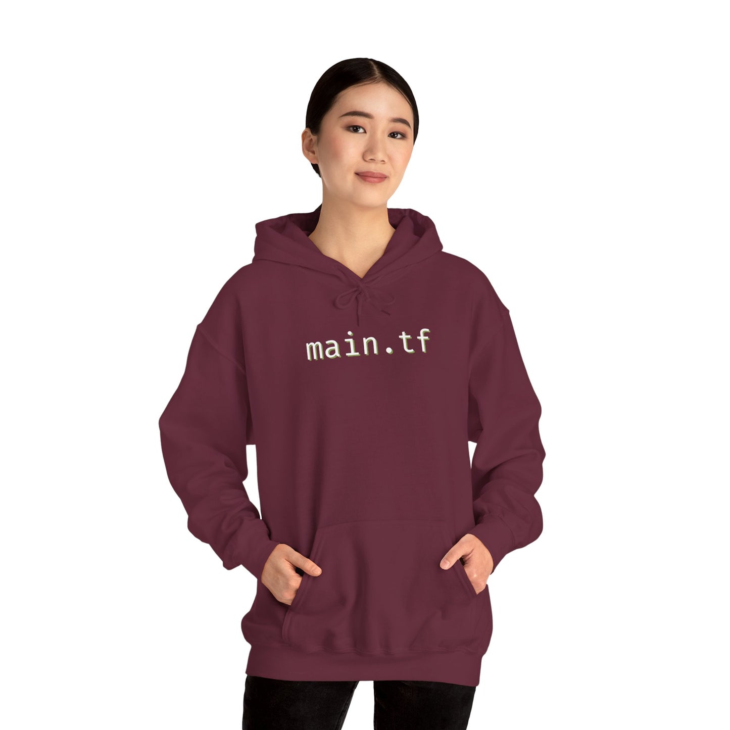 Female model fronts maroon hoodie, white "main.tf" print, hands in kangaroo pocket