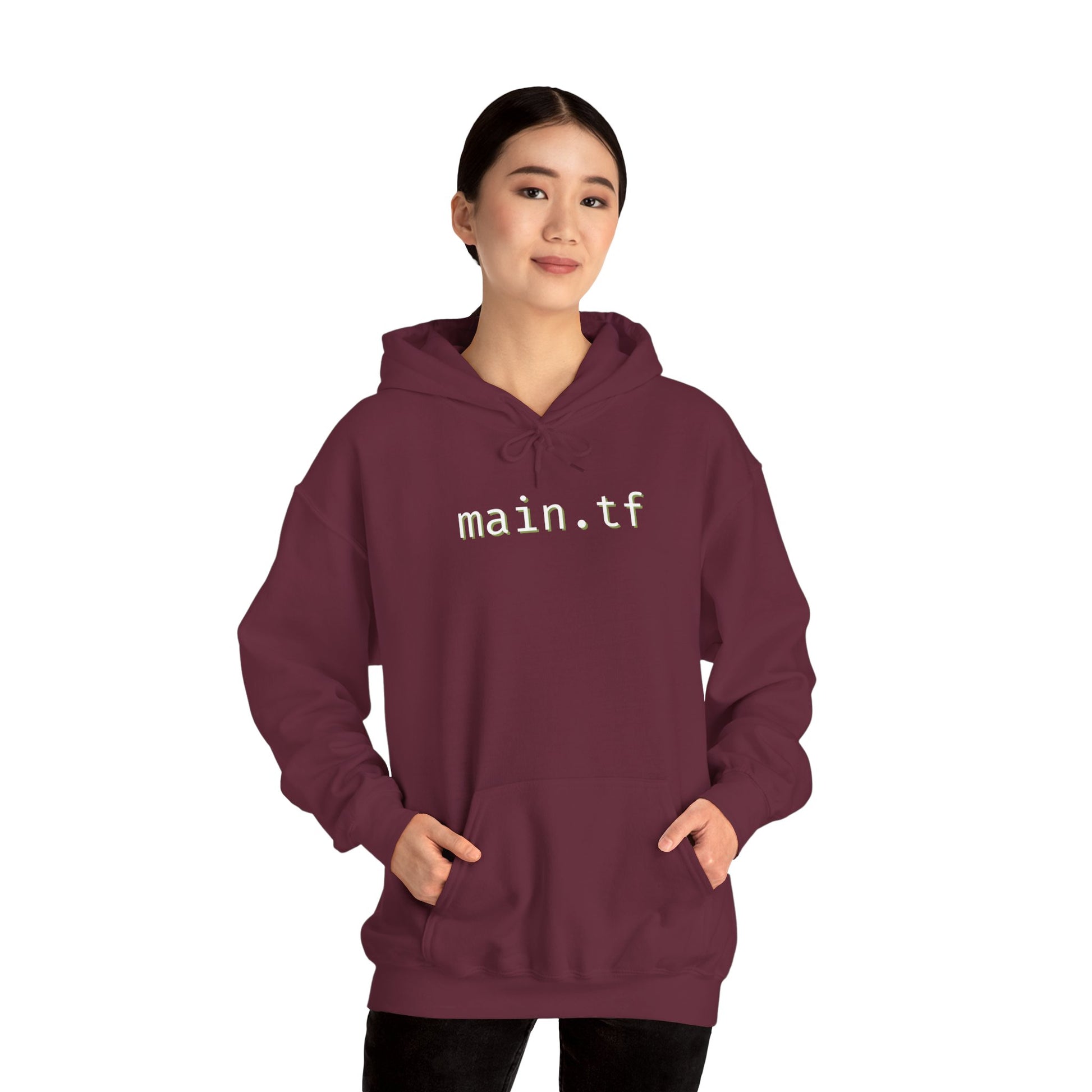 Female model fronts maroon hoodie, white "main.tf" print, hands in kangaroo pocket