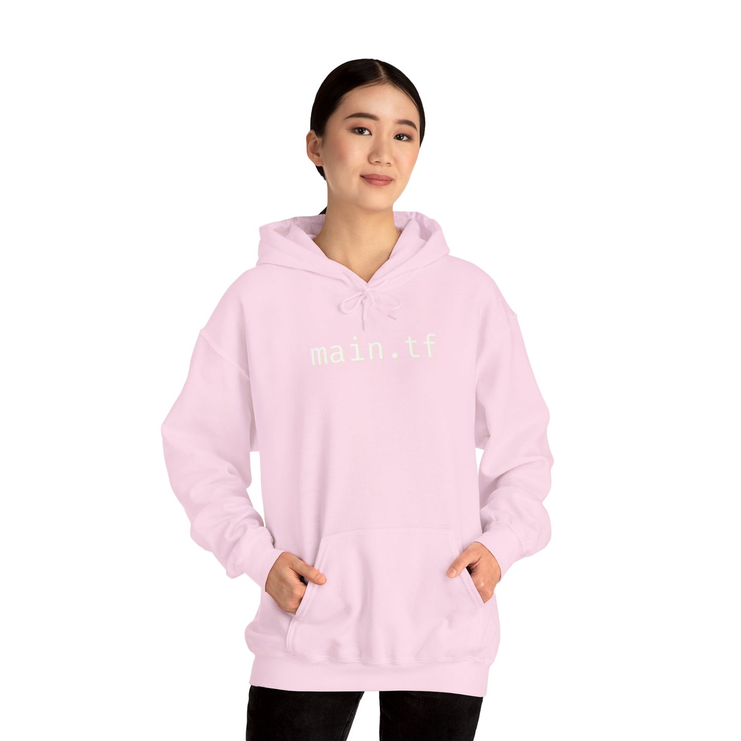 Female model front view in light pink main.tf hoodie, hands in kangaroo pocket