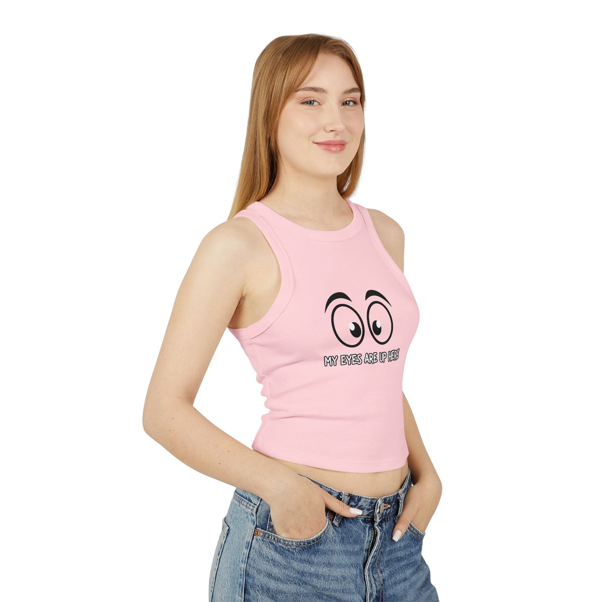 Side view of model in pink "My Eyes Are Up Here" cartoon eyes crop tank, hands in jeans pockets