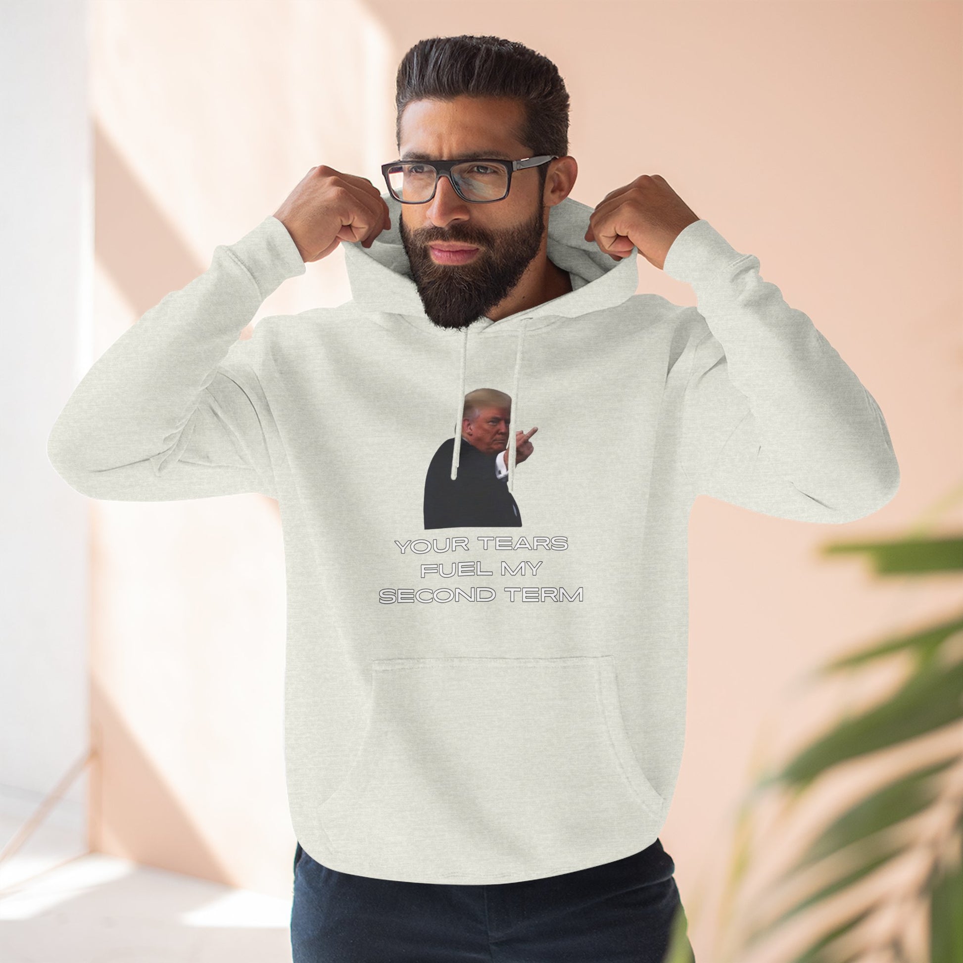 Male model pumping fists in heather gray Trump Plant hoodie, front flip-off design and slogan