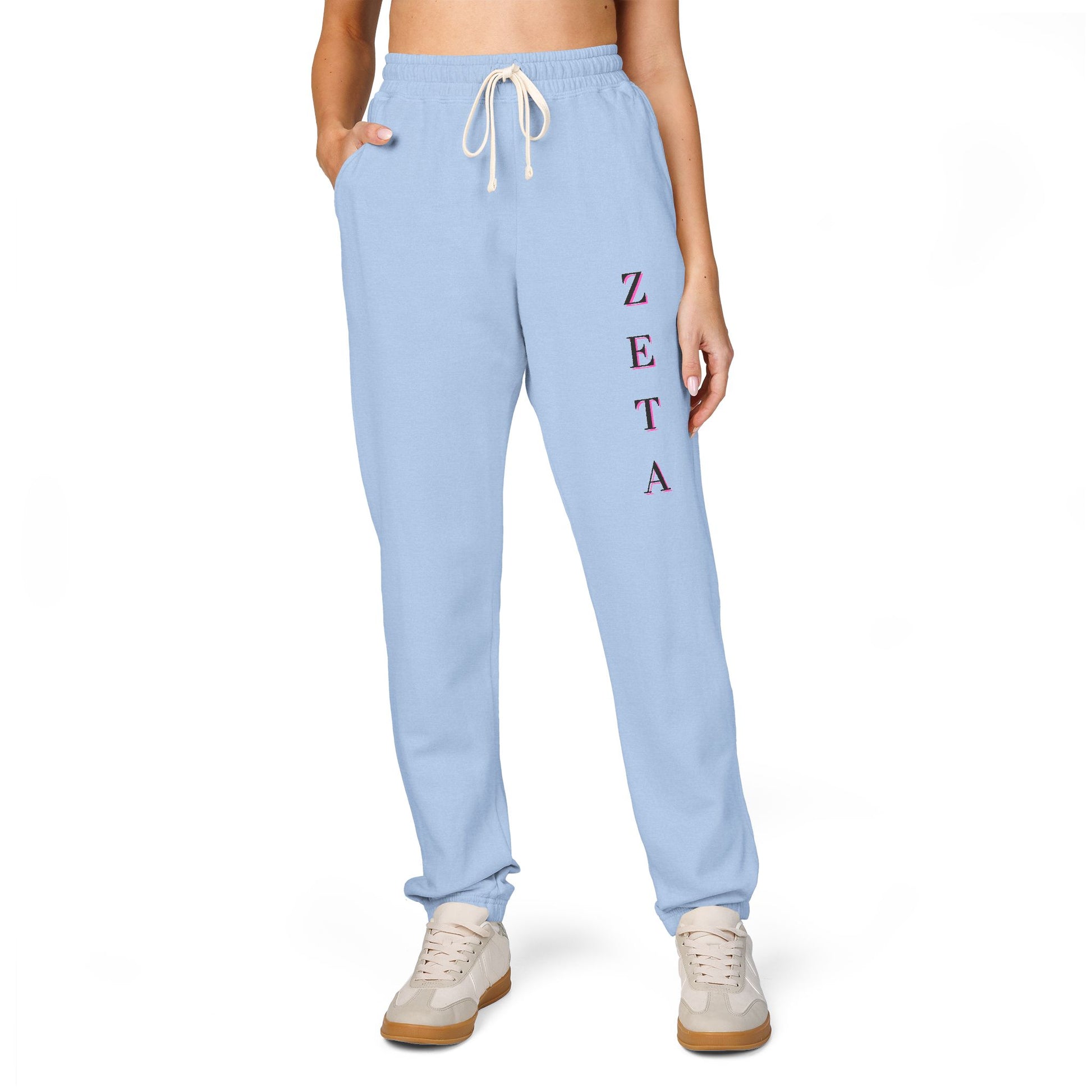 Model owning front view in light blue Zeta joggers with maroon-pink "ZETA" script on leg, white kicks