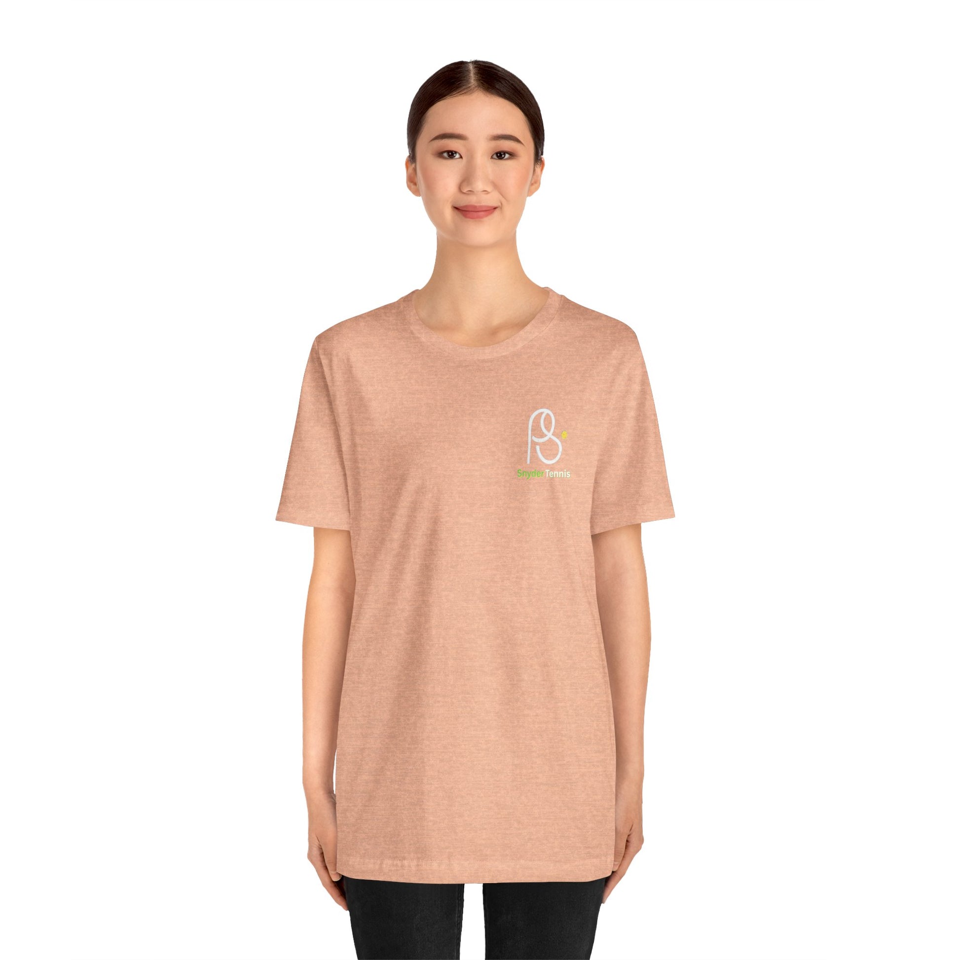 Female model front view in peach tee, wearing small white/green "P S Tennis" chest logo casually