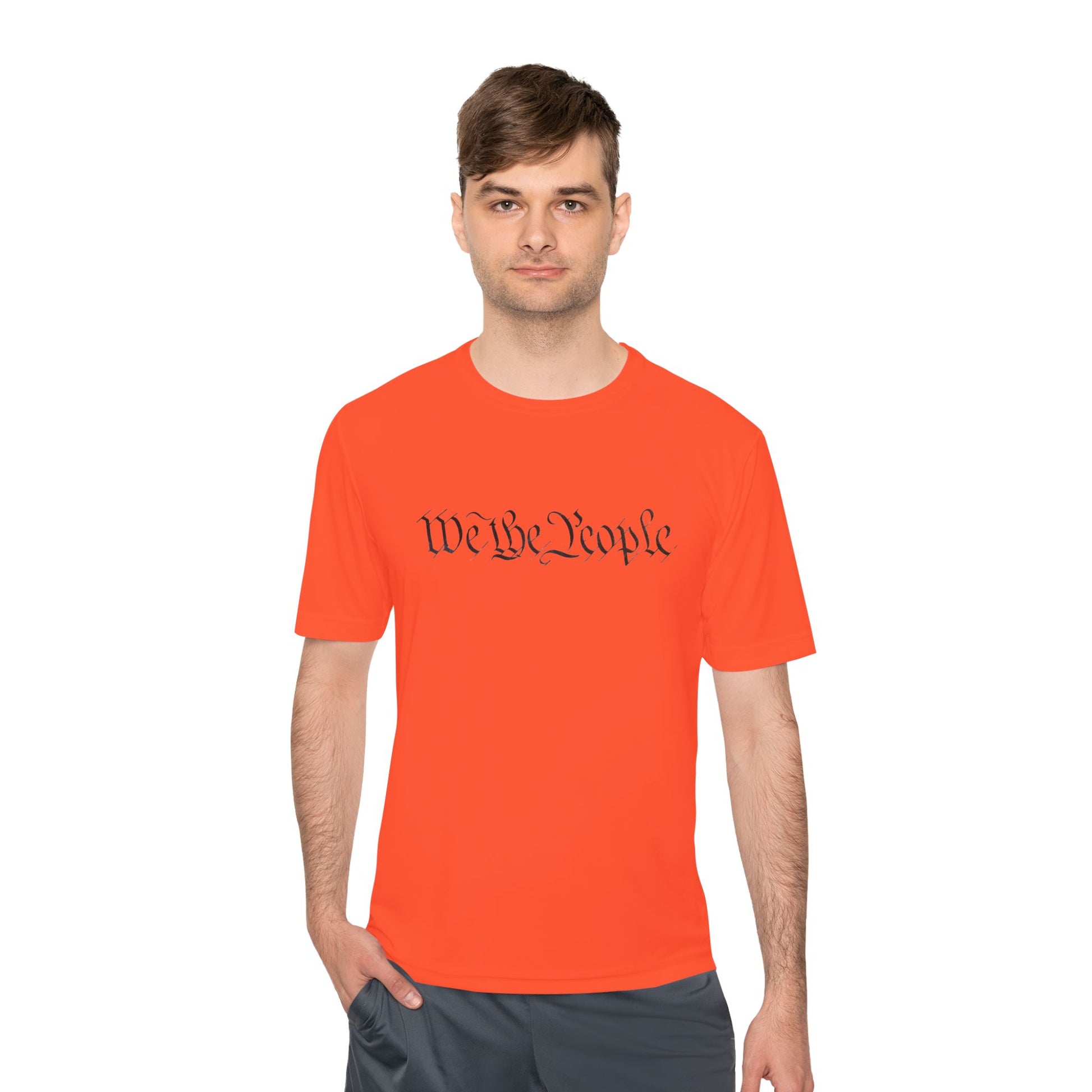 Male model sporting neon orange "We the People" cursive tee, hands in shorts pockets