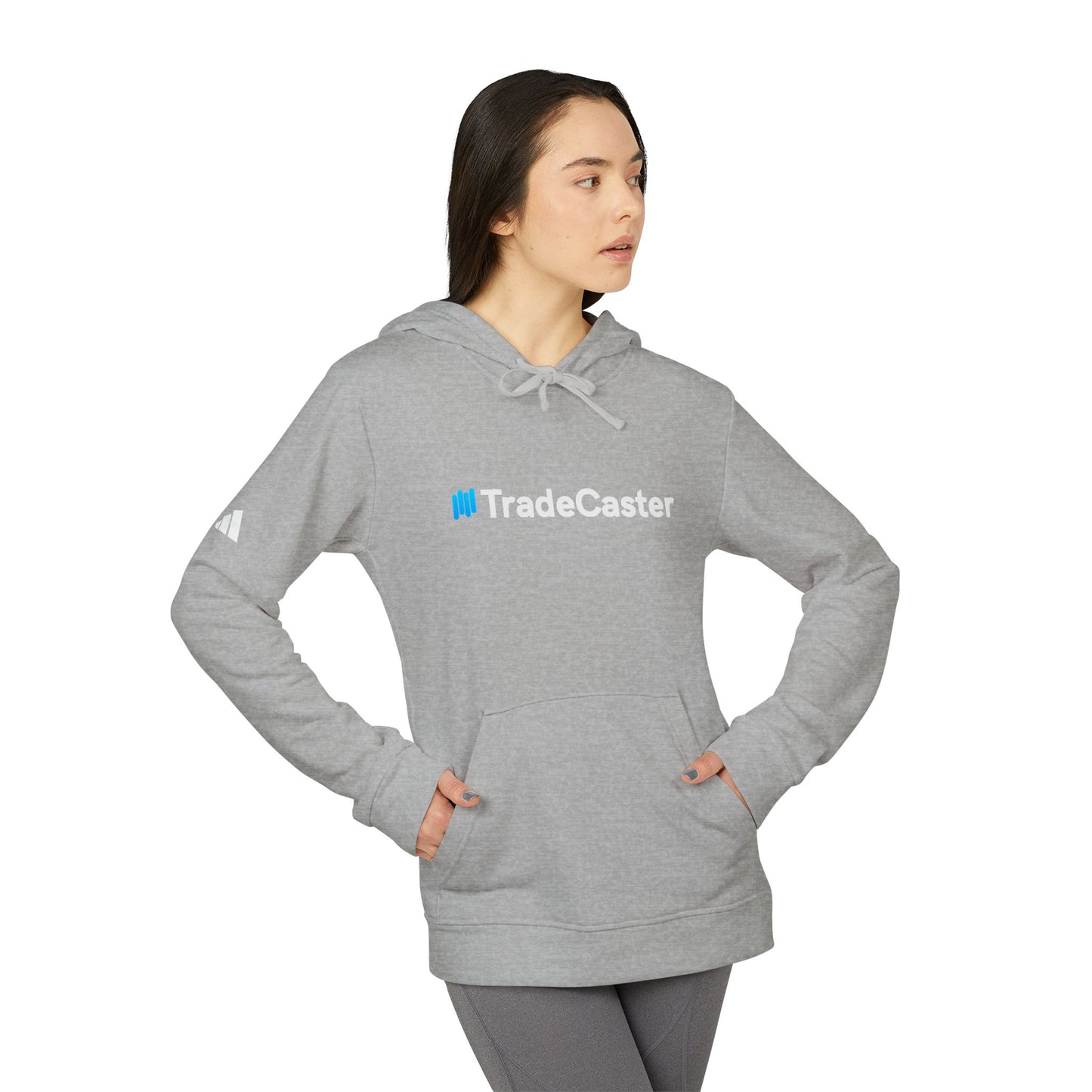 Woman side profile in grey heather TradeCaster hoodie, hands in pocket, Adidas logo visible on sleeve
