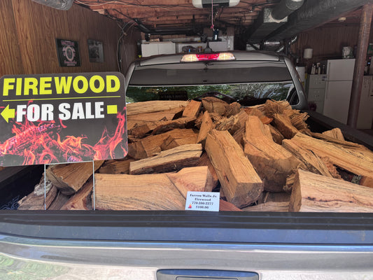 Truck bed piled high with stacked seasoned firewood, yellow "FIREWOOD FOR SALE" sign blazing flames, Farrow $100 tag in garage