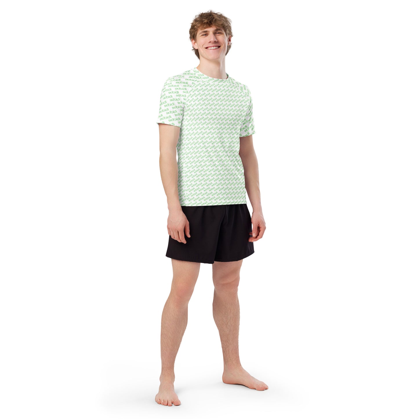 Front view of model in fitted white rash guard with green "skibidi" all-over print, black shorts, barefoot