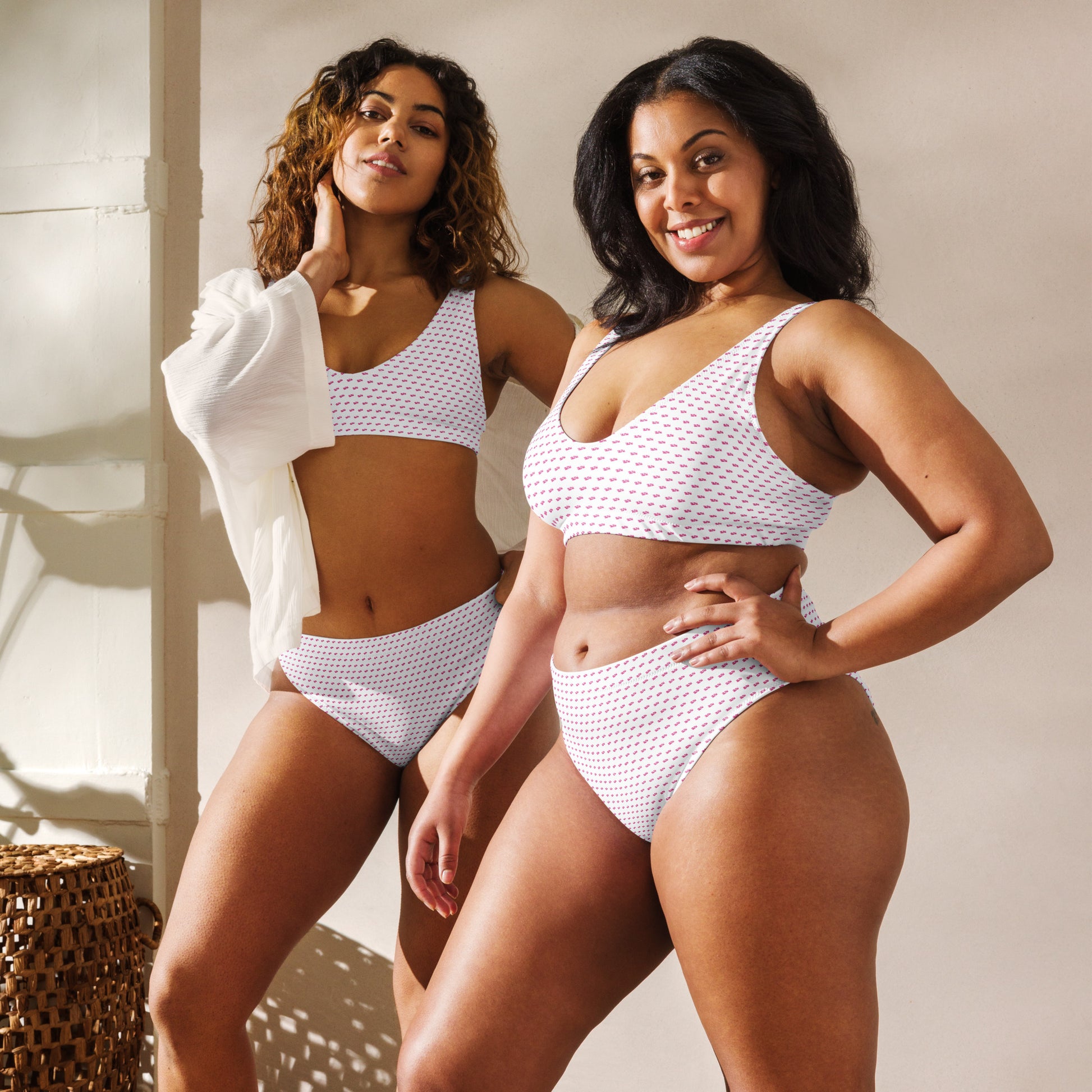 Two models posing front-on in slay recycled bikini, white with pink geometric pattern, beachy vibes
