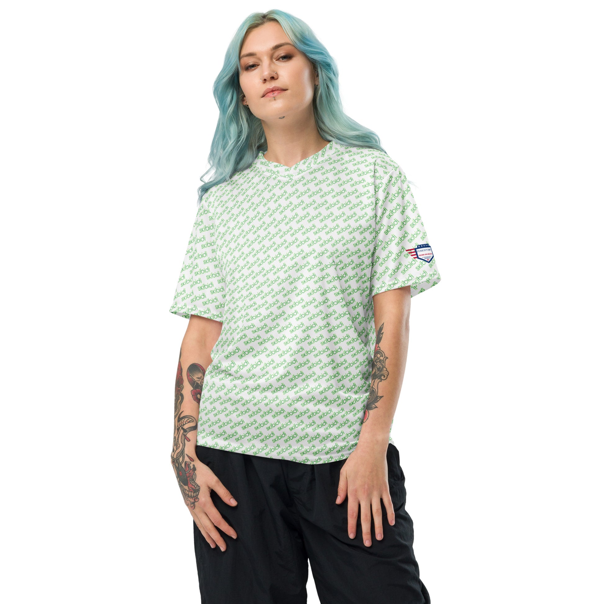 Blue-haired model flexing tattoo arm in white green "skibidi" all-over unisex sports jersey, black pants