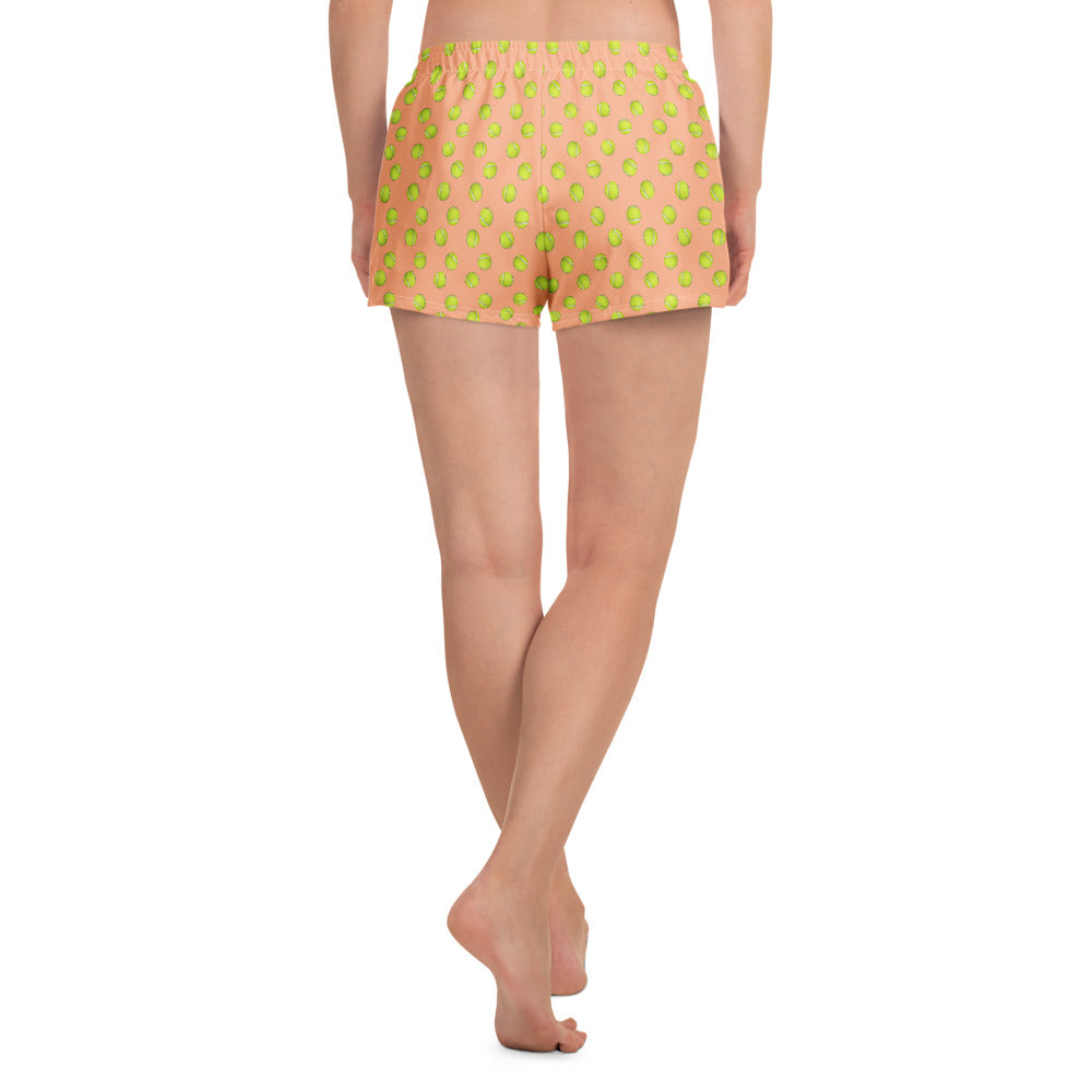 Back view of model wearing peach athletic shorts with full green tennis ball pattern, super short cut