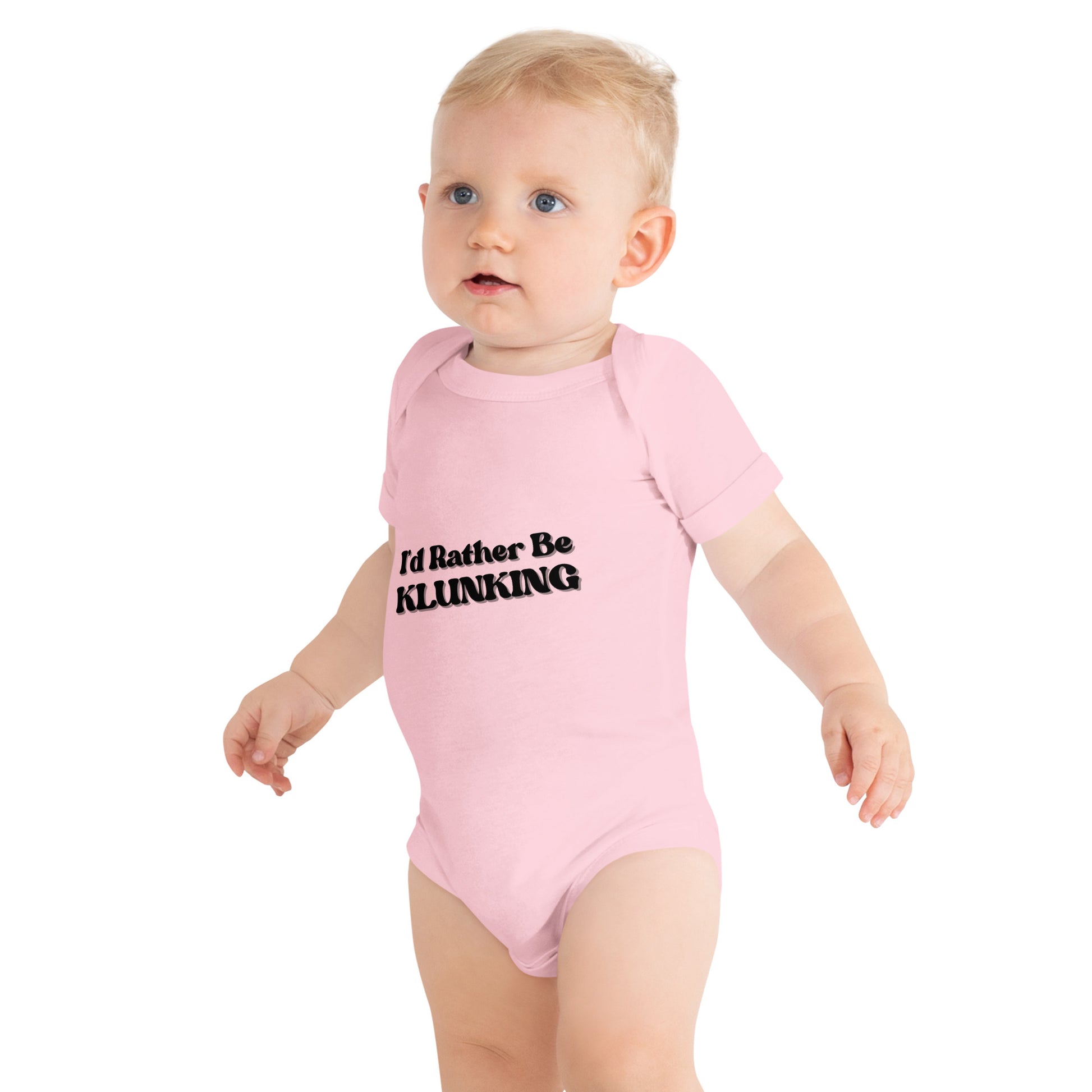Side view baby strolling in pink "I’d Rather Be KLUNKING" short sleeve one piece