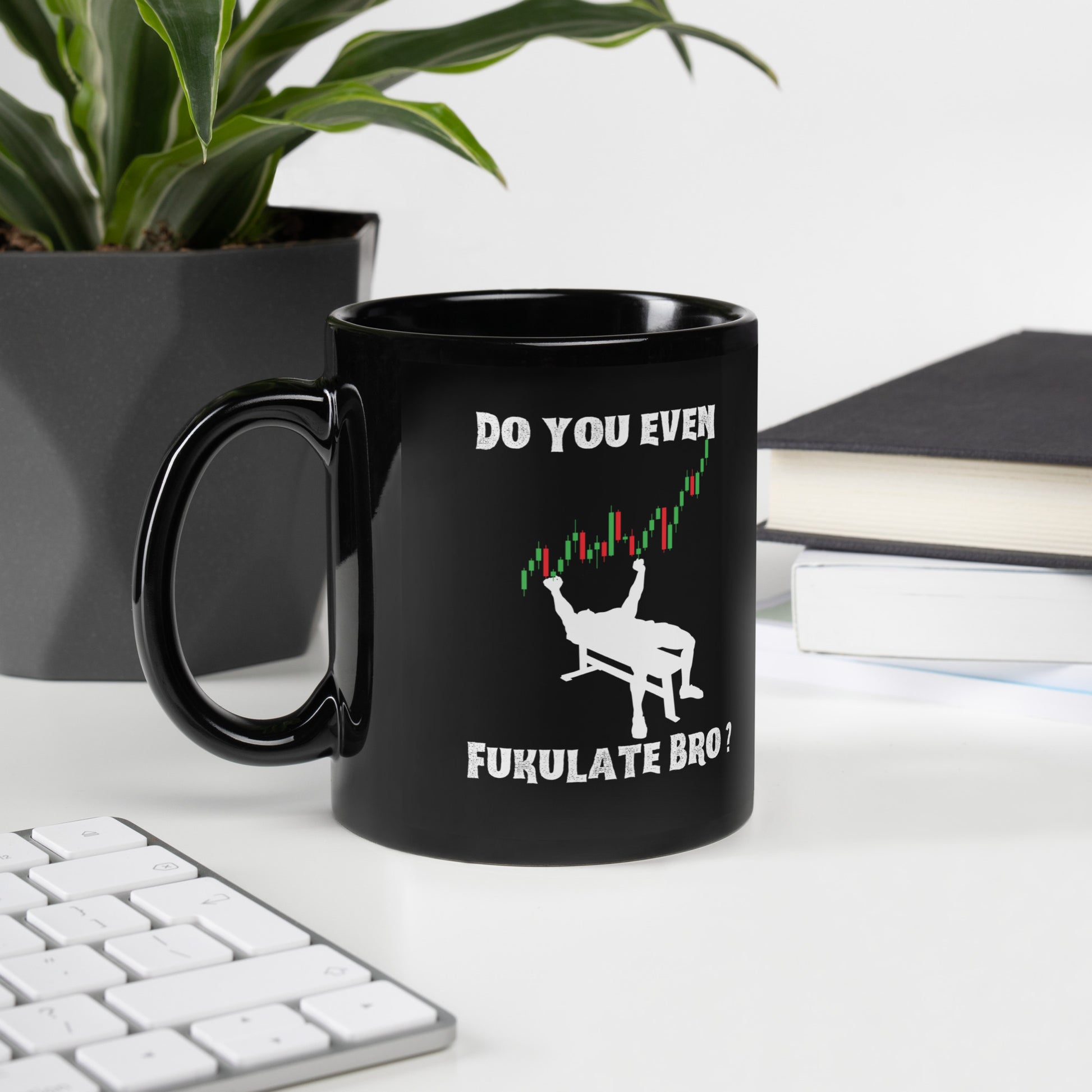 Desk vibe with glossy black "Do You Even FUKULATE" mug, green plant left, books and keyboard right