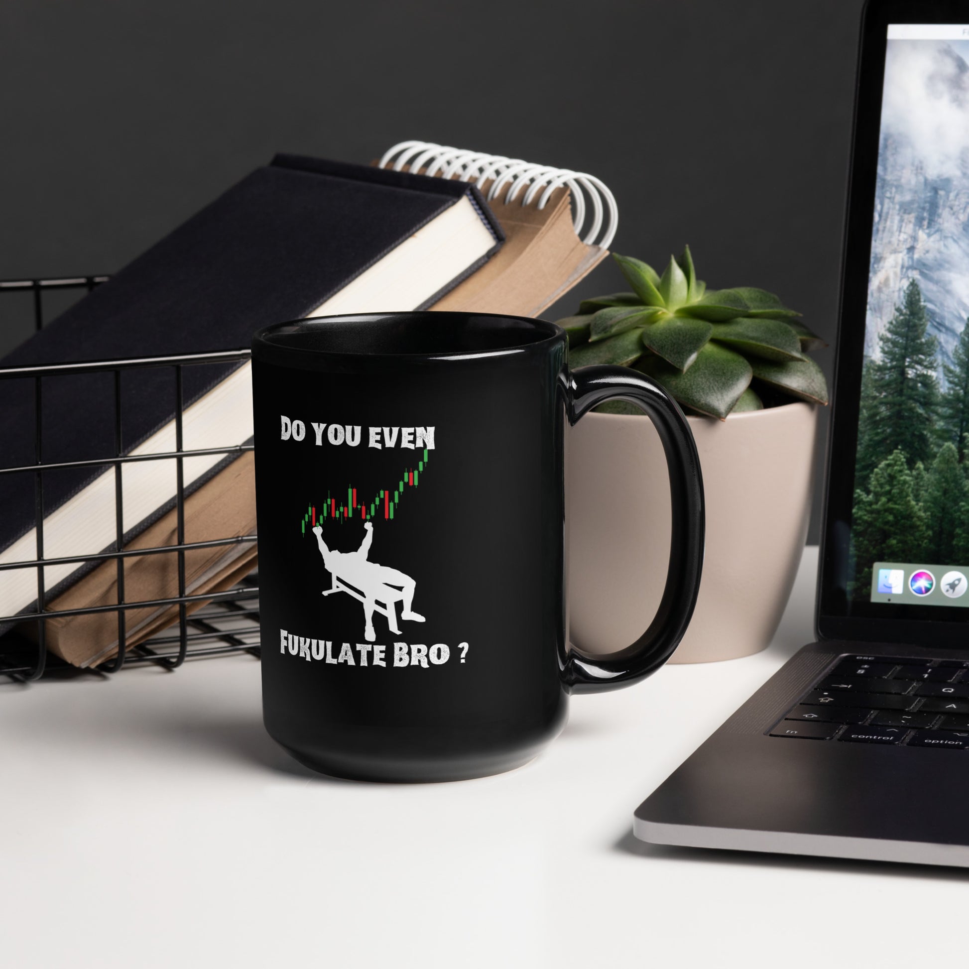 Black mug with "FUKULATE BRO?" print on workspace desk next to plant, books, and keyboard