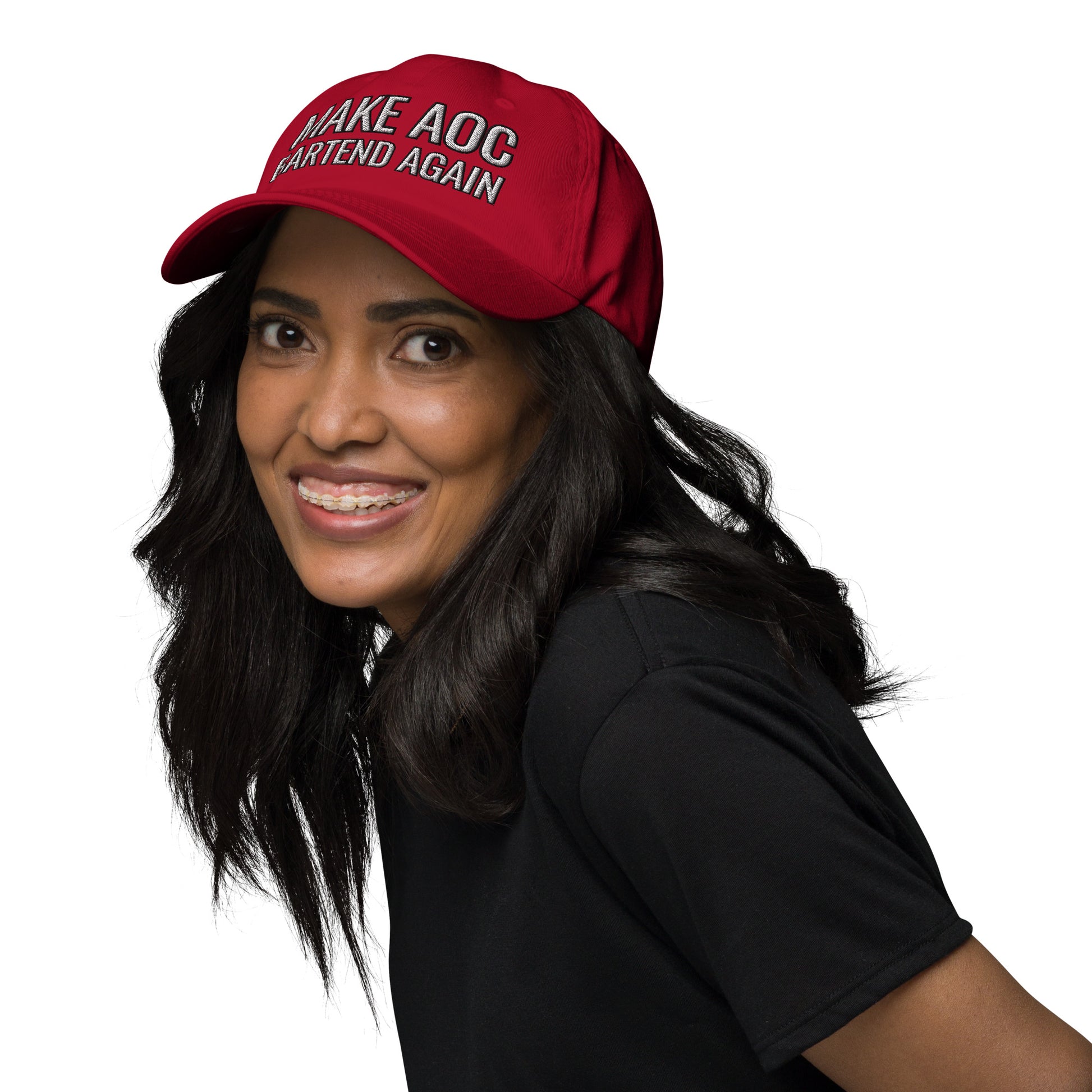 Smiling model in black top wearing red dad hat with white "Make AOC Bartend Again" embroidery, front-left view