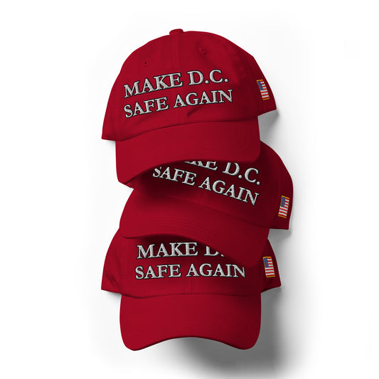 Top-down stack of three red dad hats with white "Make D.C. Safe Again" embroidery and tiny US flag patches peeking out