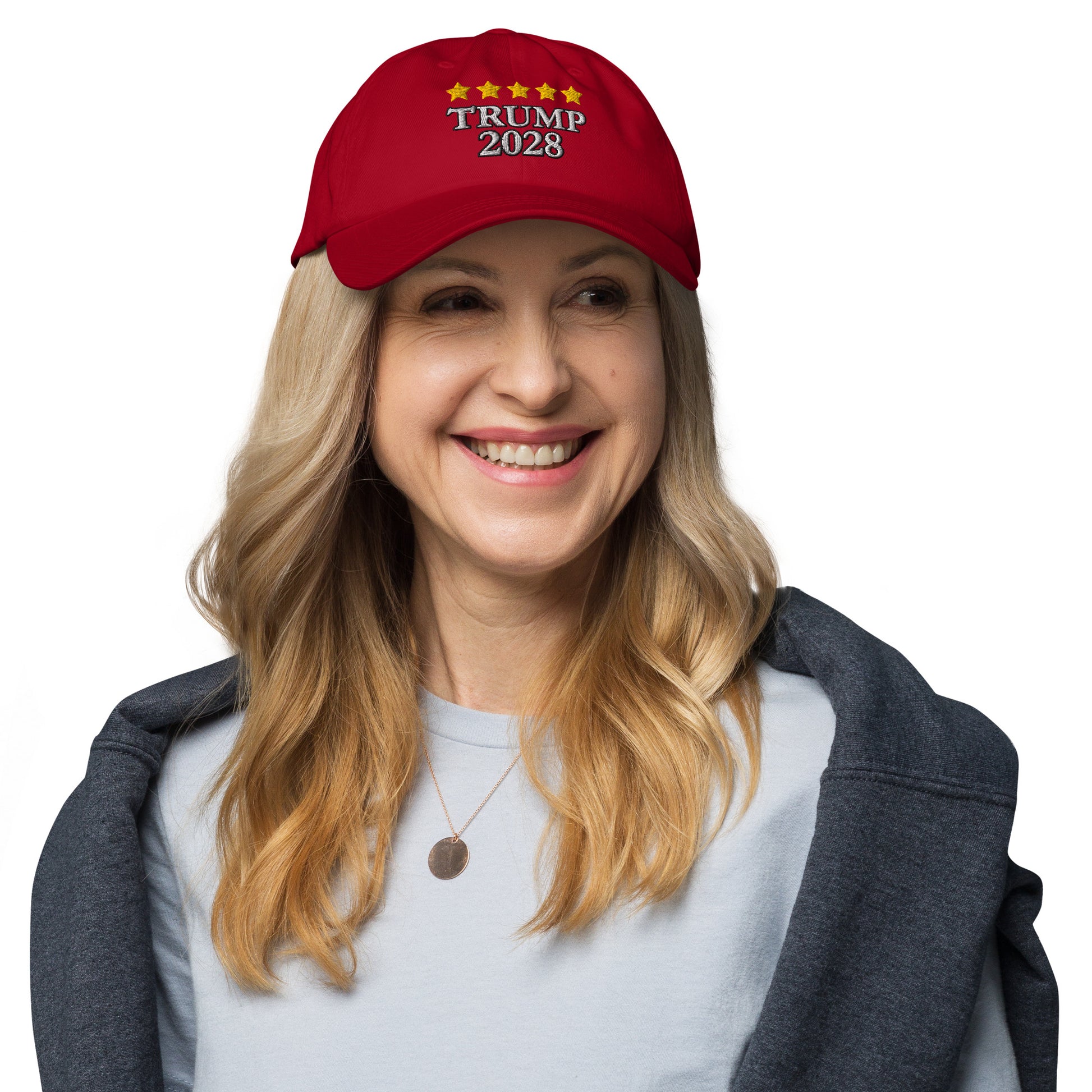 Blonde woman grinning in gray top, front view of red dad hat with "TRUMP 2028" and gold stars
