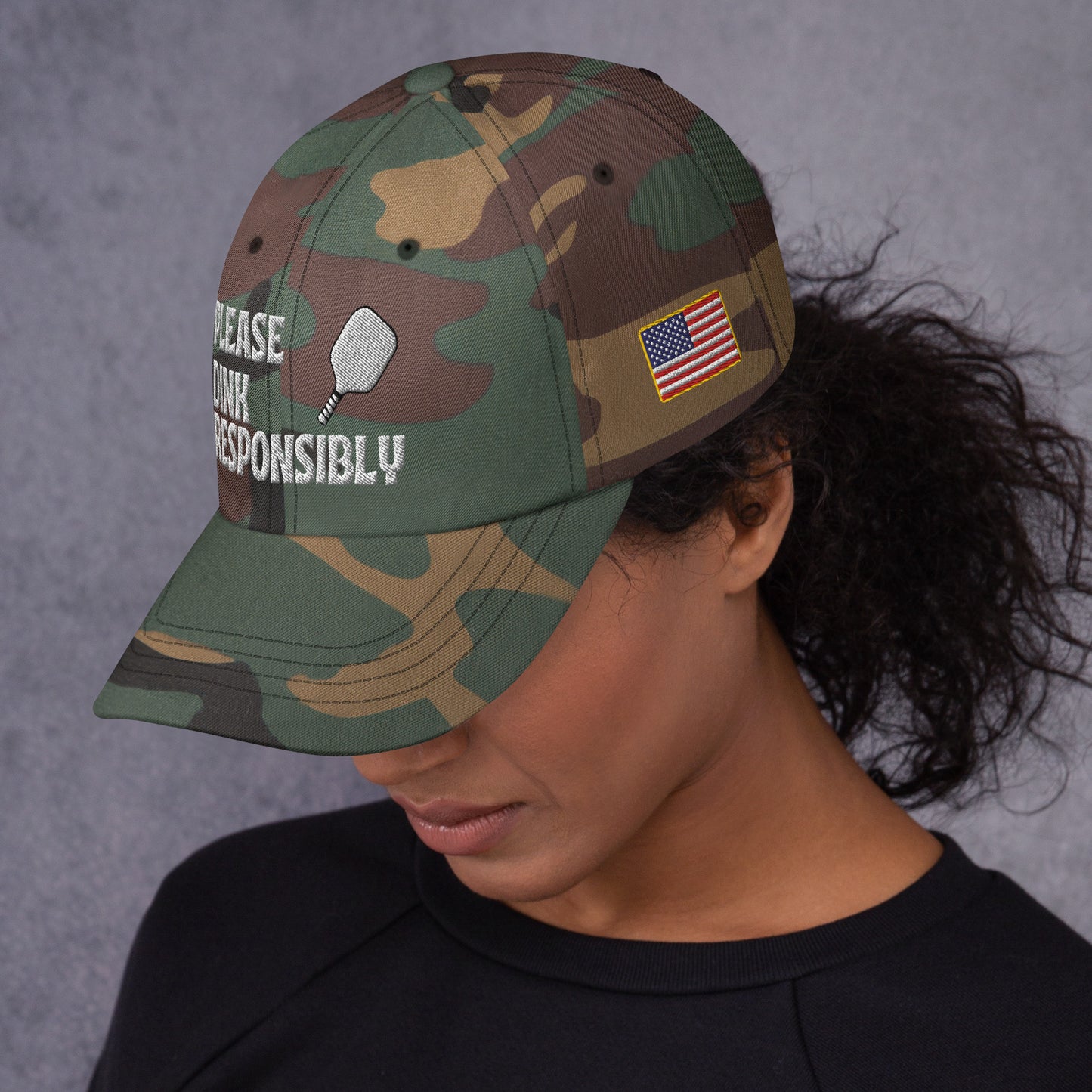 Side profile of green camo dad hat on model with "PLEASE DINK RESPONSIBLY" text, paddle, and US flag patch